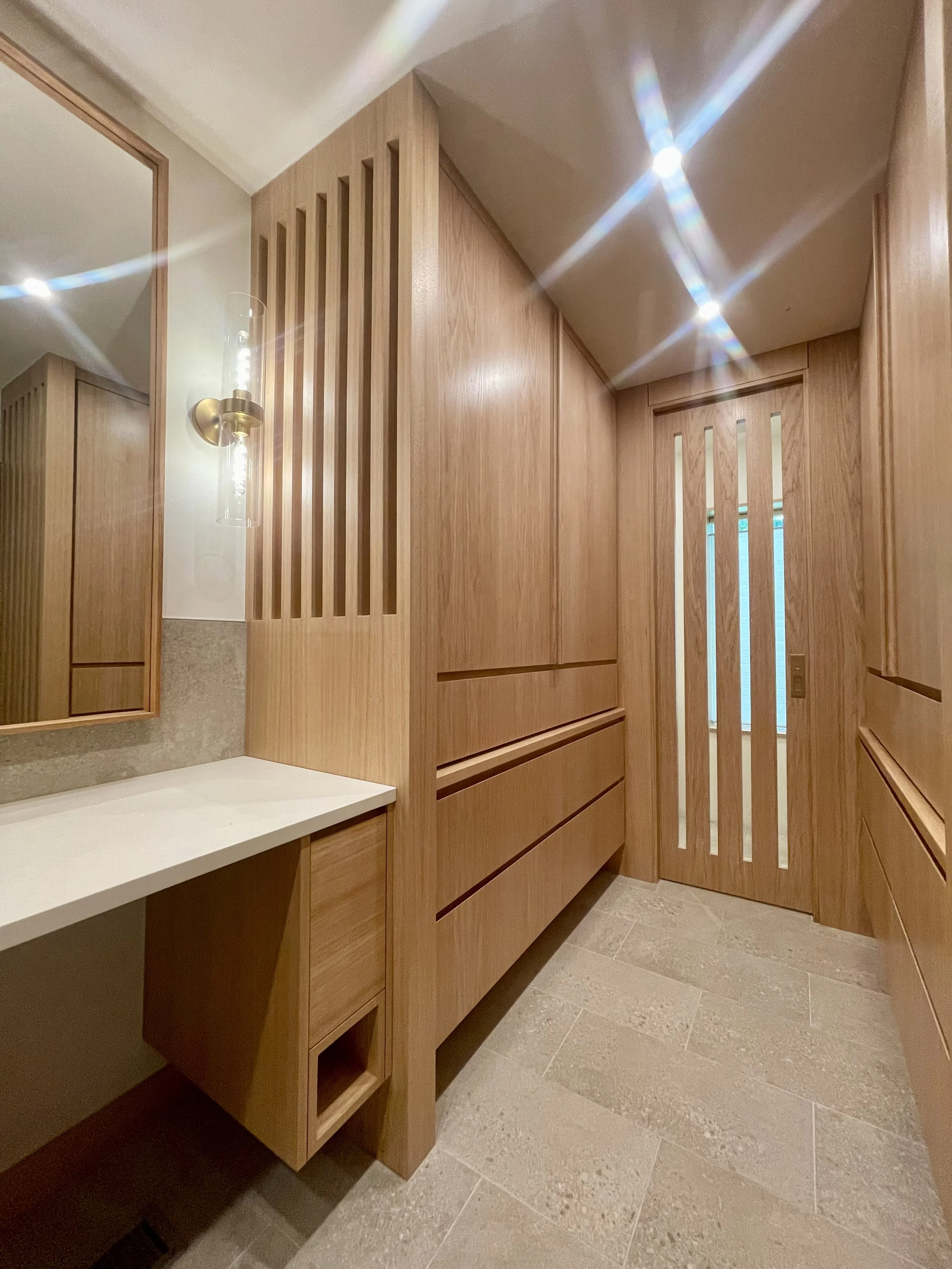 Mirrored Grain-Matched Wardrobe & Pocket Door and Architectural Partition Walls in Uniform Hickory Veneer & Hardwood Finished with Centurion 2K Polyurethane.

Wall Mounted Lighting Fixture is Kohler Purist in Vibrant Brushed Modern Gold. 

Bathroom R