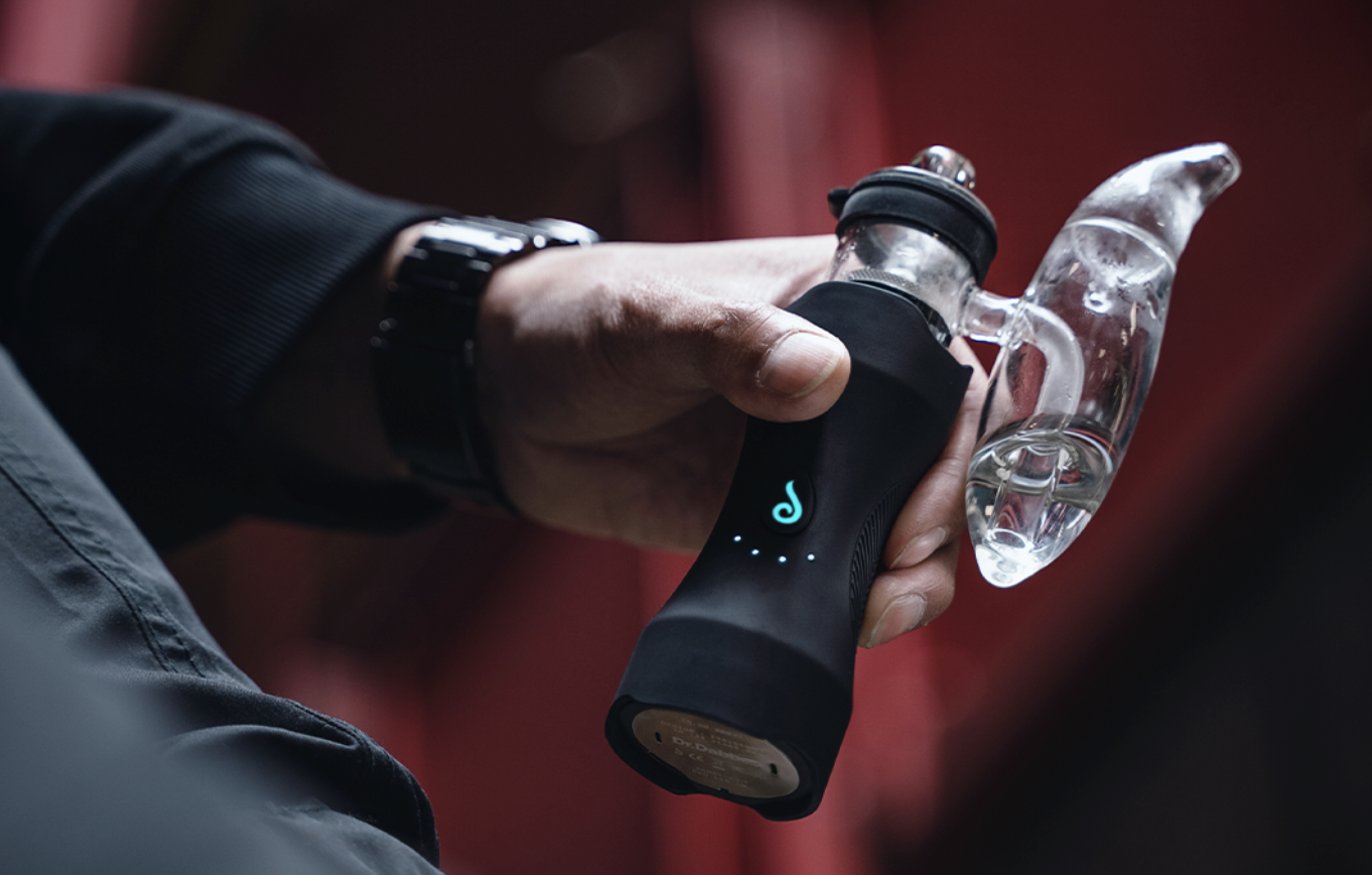 Ein Mann hält den luxus Vaporizer XS von Dr. Dabber in seiner Hand. Alles vorbereitet zum Dabben von extrakten.