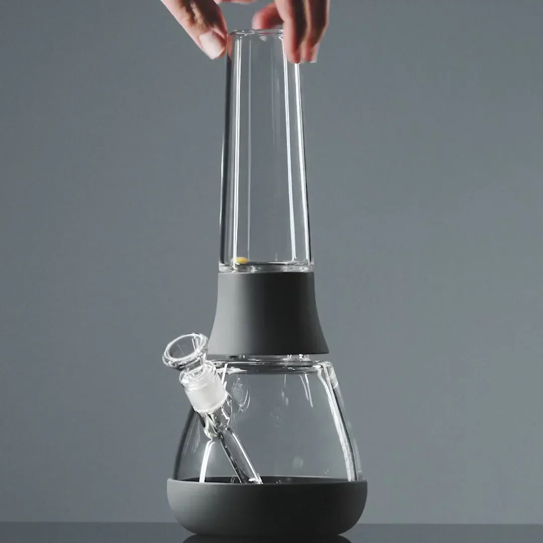 Minimalistisches Lifestylefoto: Hand hält Weeday Bong in Charcoal vor farbigem Hintergrund.