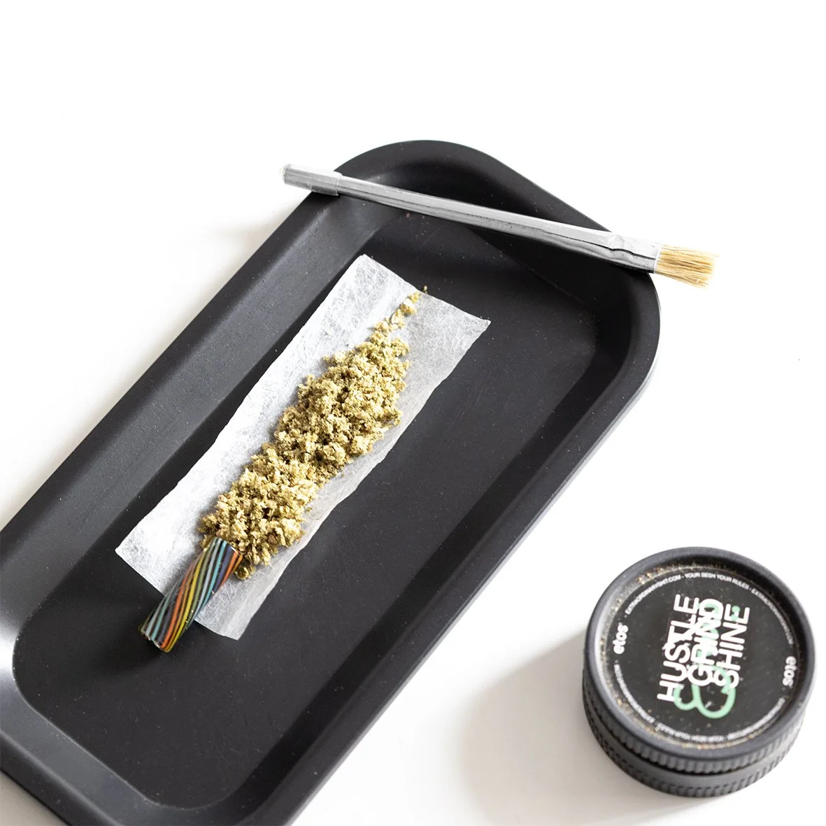 das fertige paper mit Galsfilter und fluffig gegrindetem Material liegt zusammen it dem Twin Tip Naturhaarpinsel und Joint Poker auf dem hanf Drehtablett von etos*.