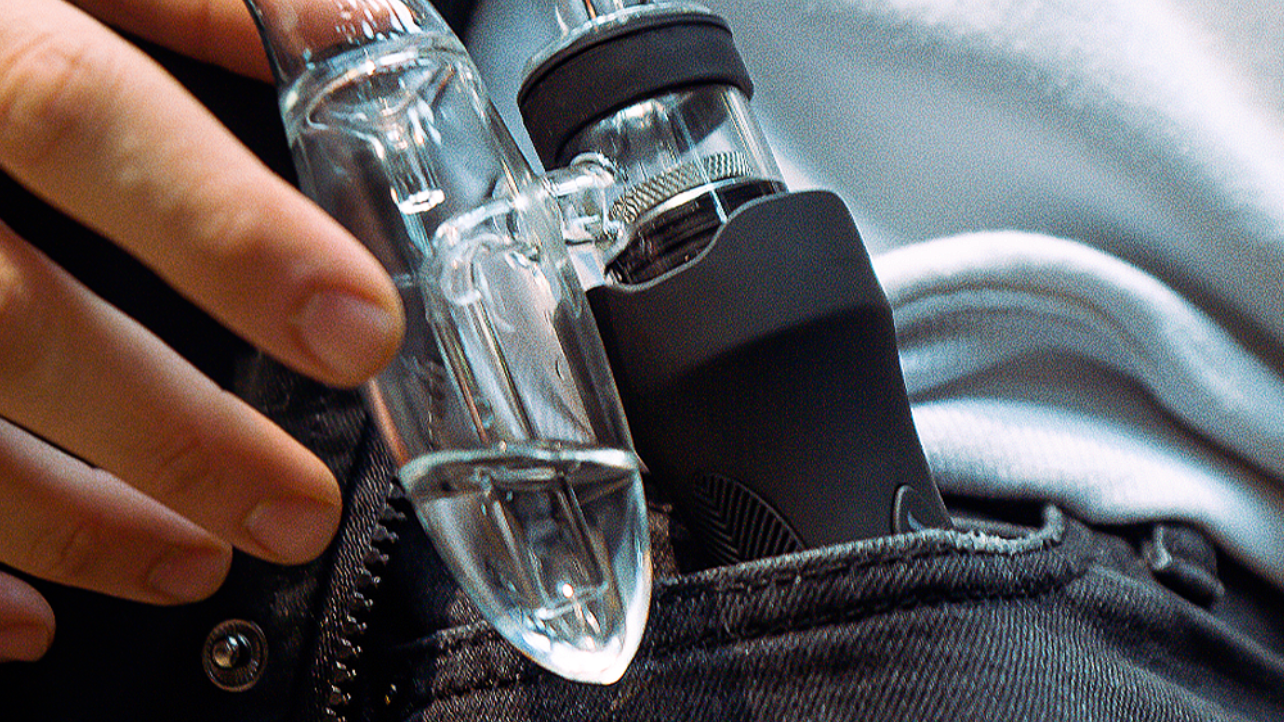 Eine gand zieht den Dr Dabber XS premium Vaporizer aus der Hosentasche. Die hochwertige technik des Gerätes ist gut sichtbar.