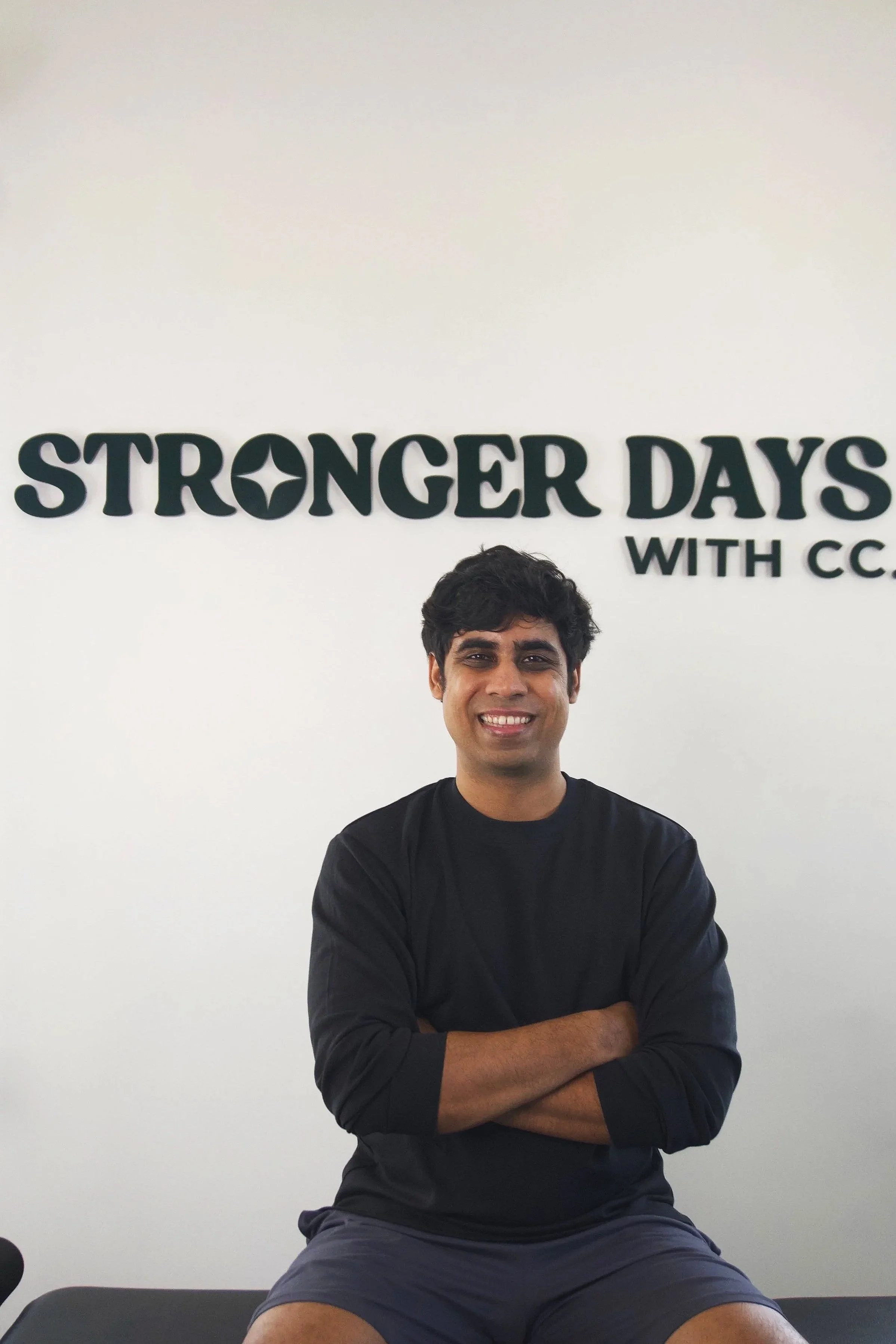 Chirag Chordia sitting with arms crossed under a Stronger Days with CC wall logo.