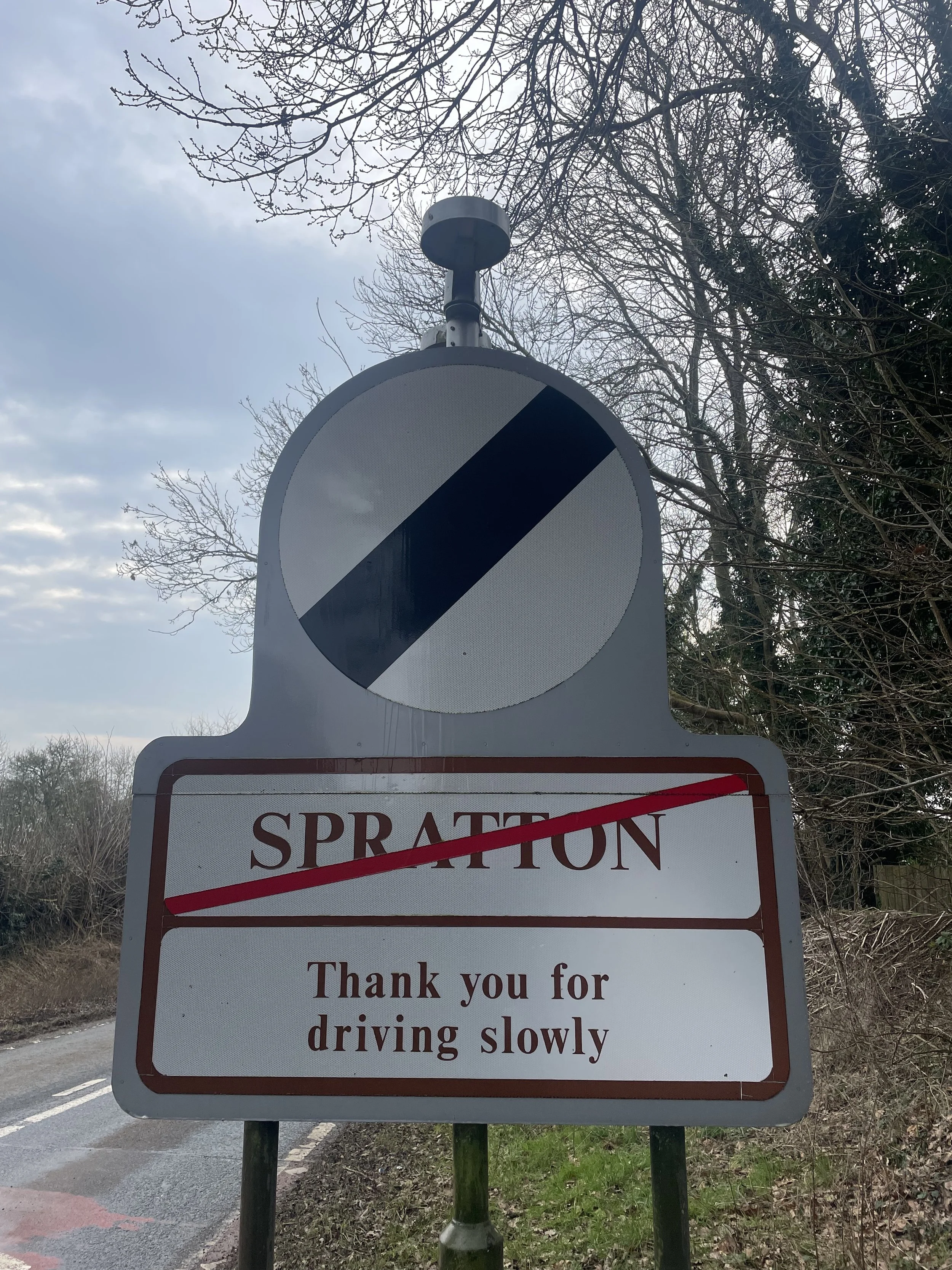 A road sign indicating the end of a levied zone, with a message thanking drivers for driving slowly.
