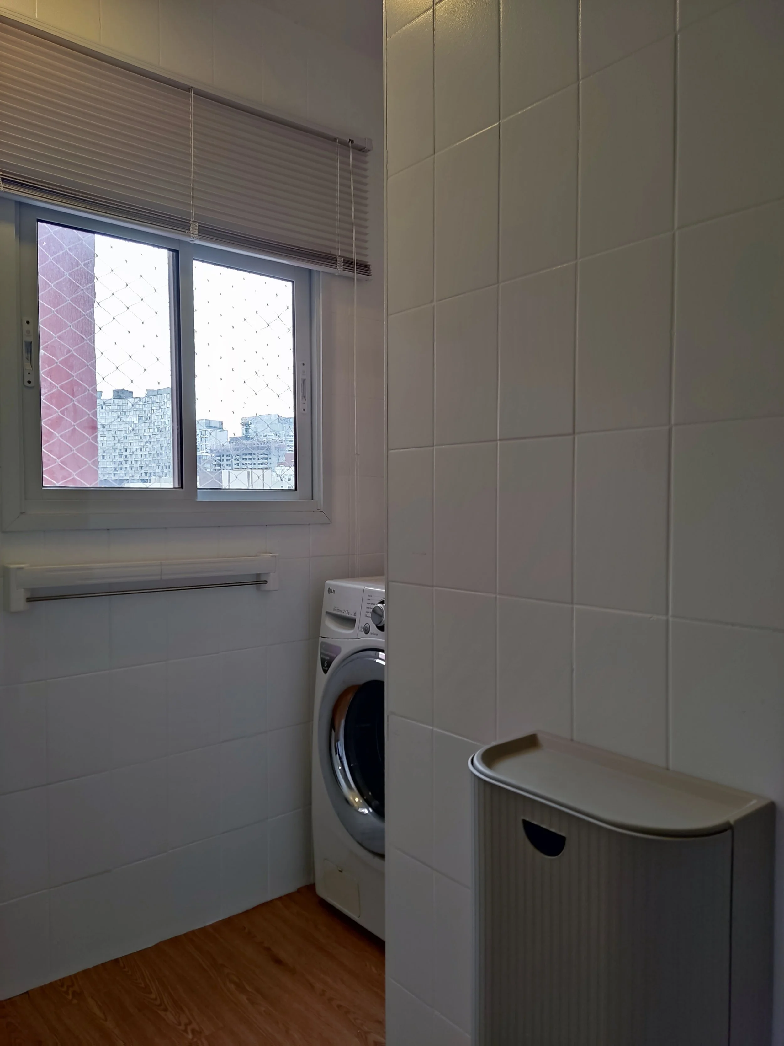 Lavanderia com janela, máquina de lavar roupa, revestimento de azulejos brancos e radiação de luz natural