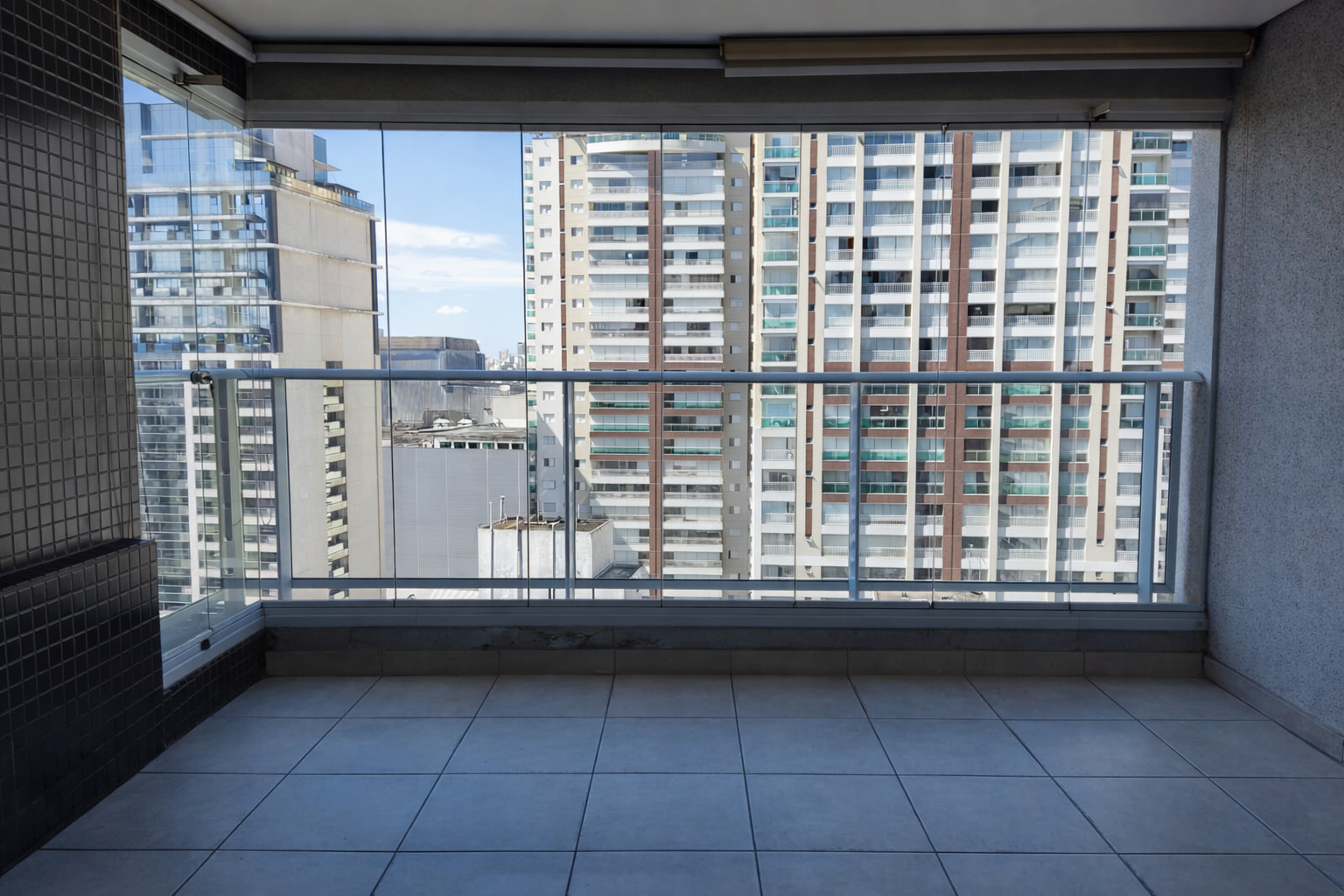 Varanda de apartamento com vista para prédios altos e céu azul.