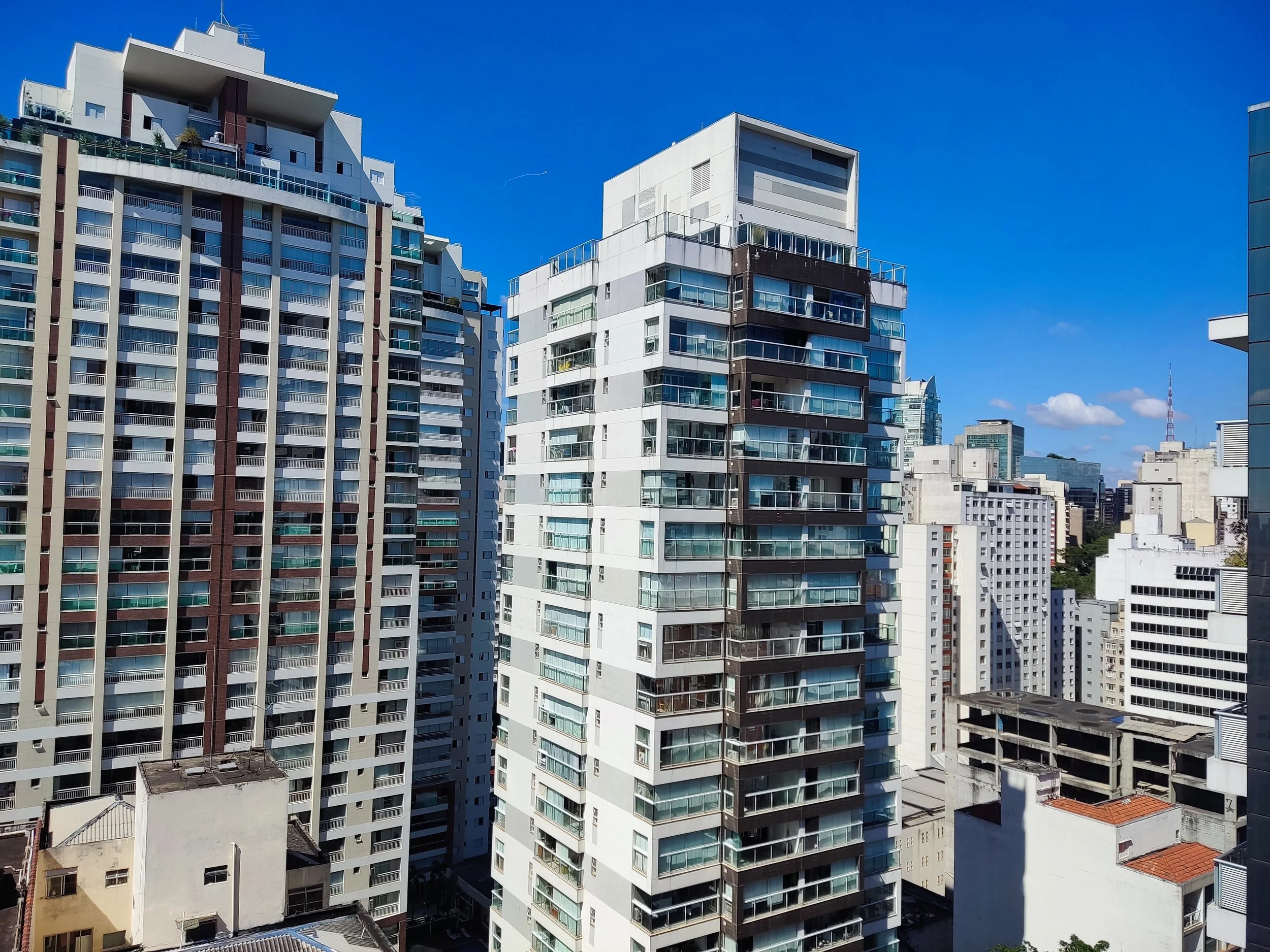 Prédios residenciais altos em uma cidade com céu azul claro e poucas nuvens.