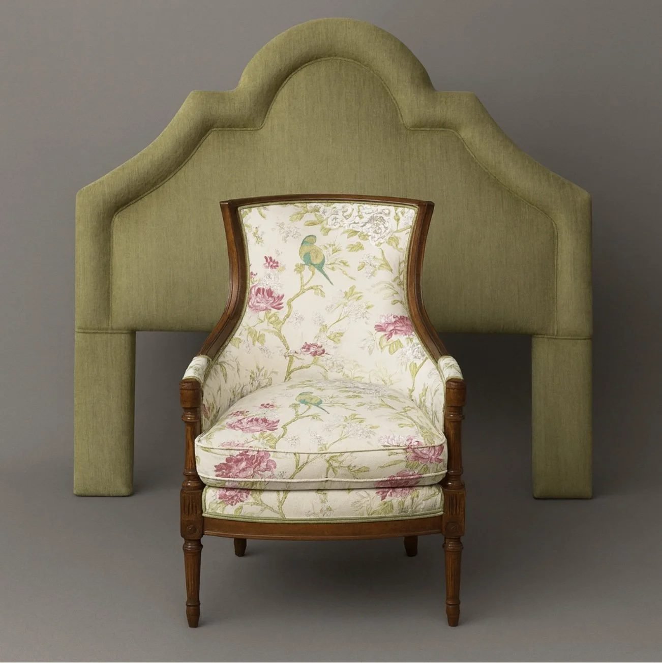 A restored armchair with a hand-carved wood frame and floral upholstery