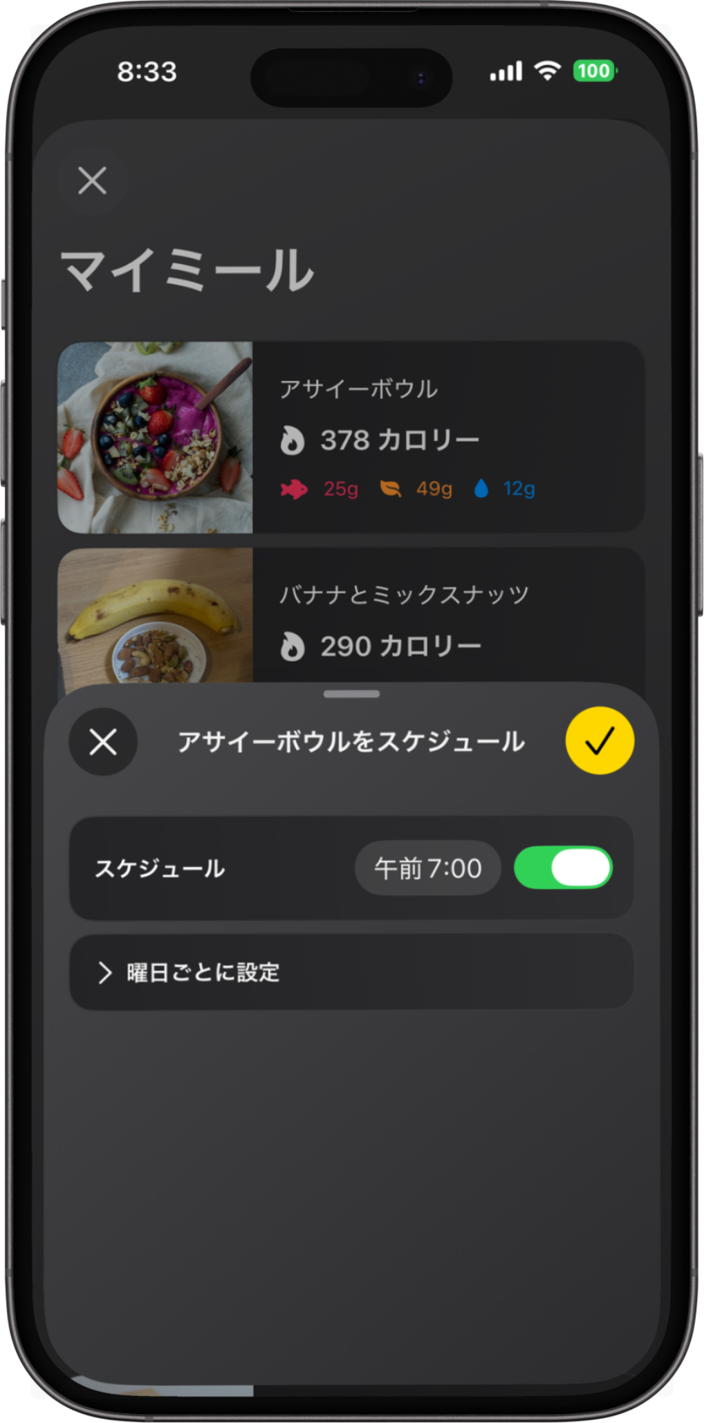 スマートフォンのスクリーンに表示された食事管理アプリの画面。アサイーボウルやバナナとミックスナッツの写真と、そのカロリーや栄養情報が示されている。