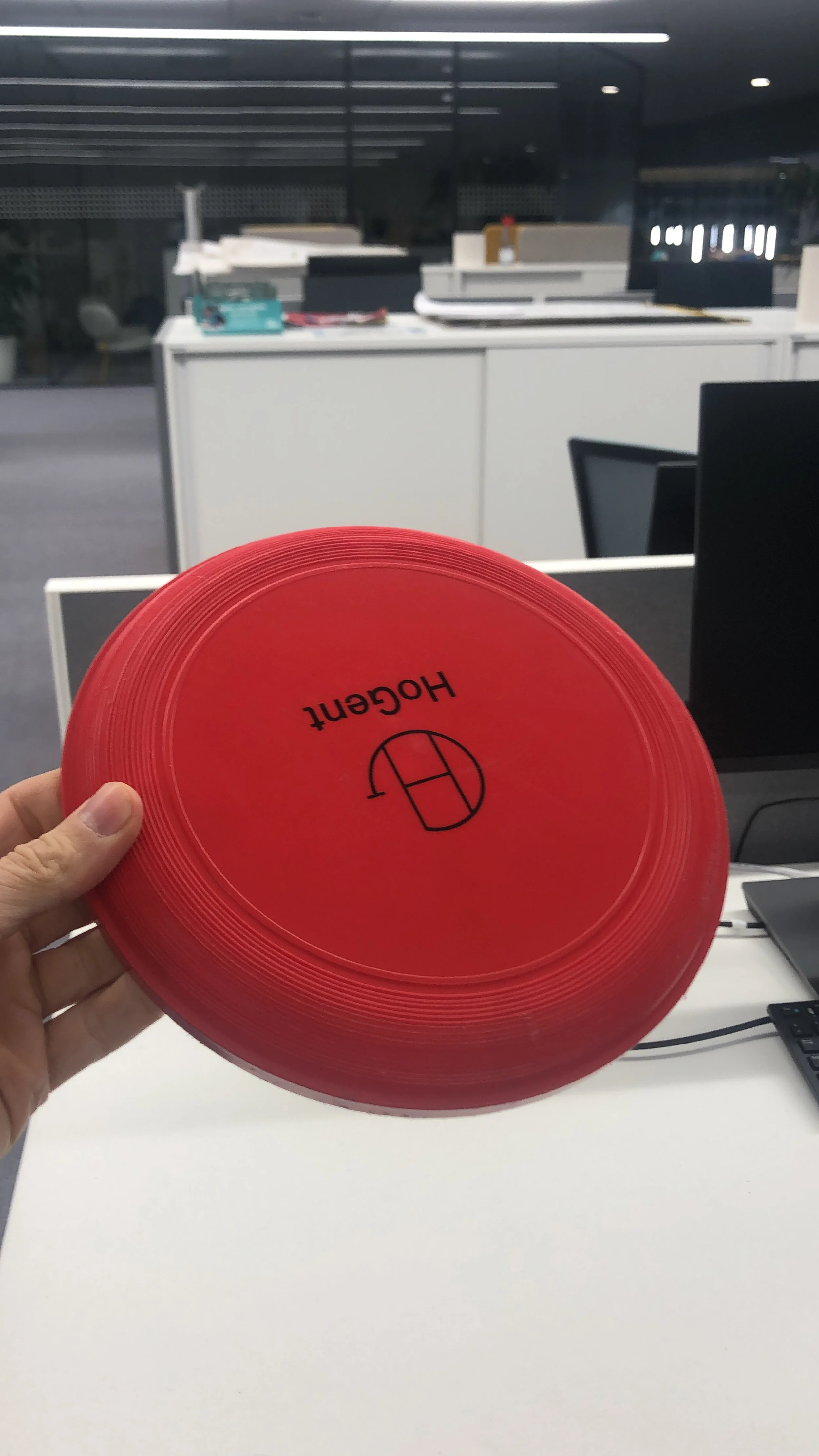 Een rode disc, bedoeld voor tennis, met het logo en de naam 'Houten'.