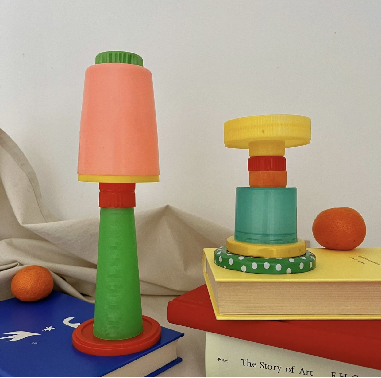 Colorful stacking toy balls and a book with oranges in the background and a white backdrop.