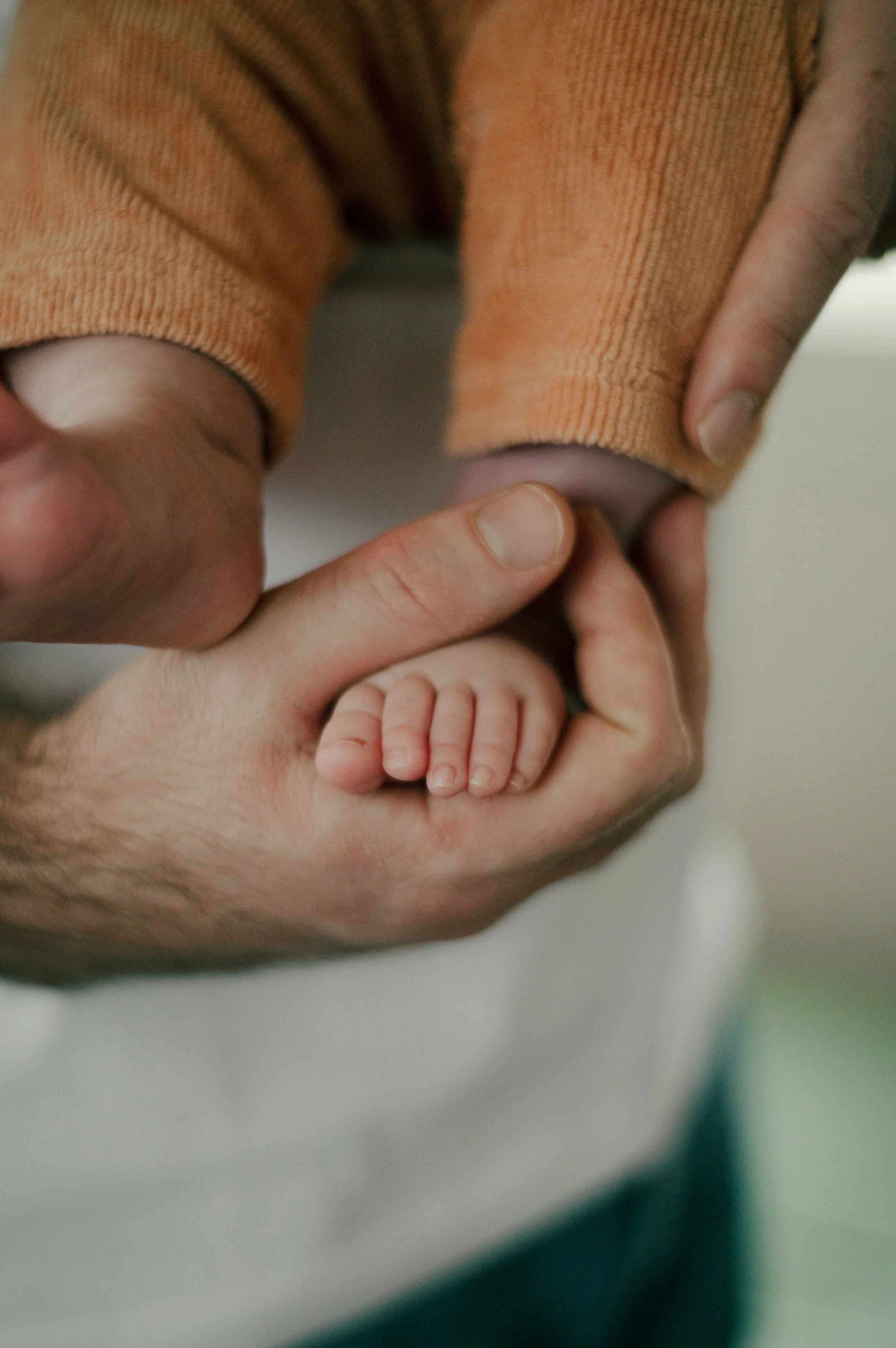 Lapsen varpaat ja aikuisen käsi, joka pitelee jalkaa.
