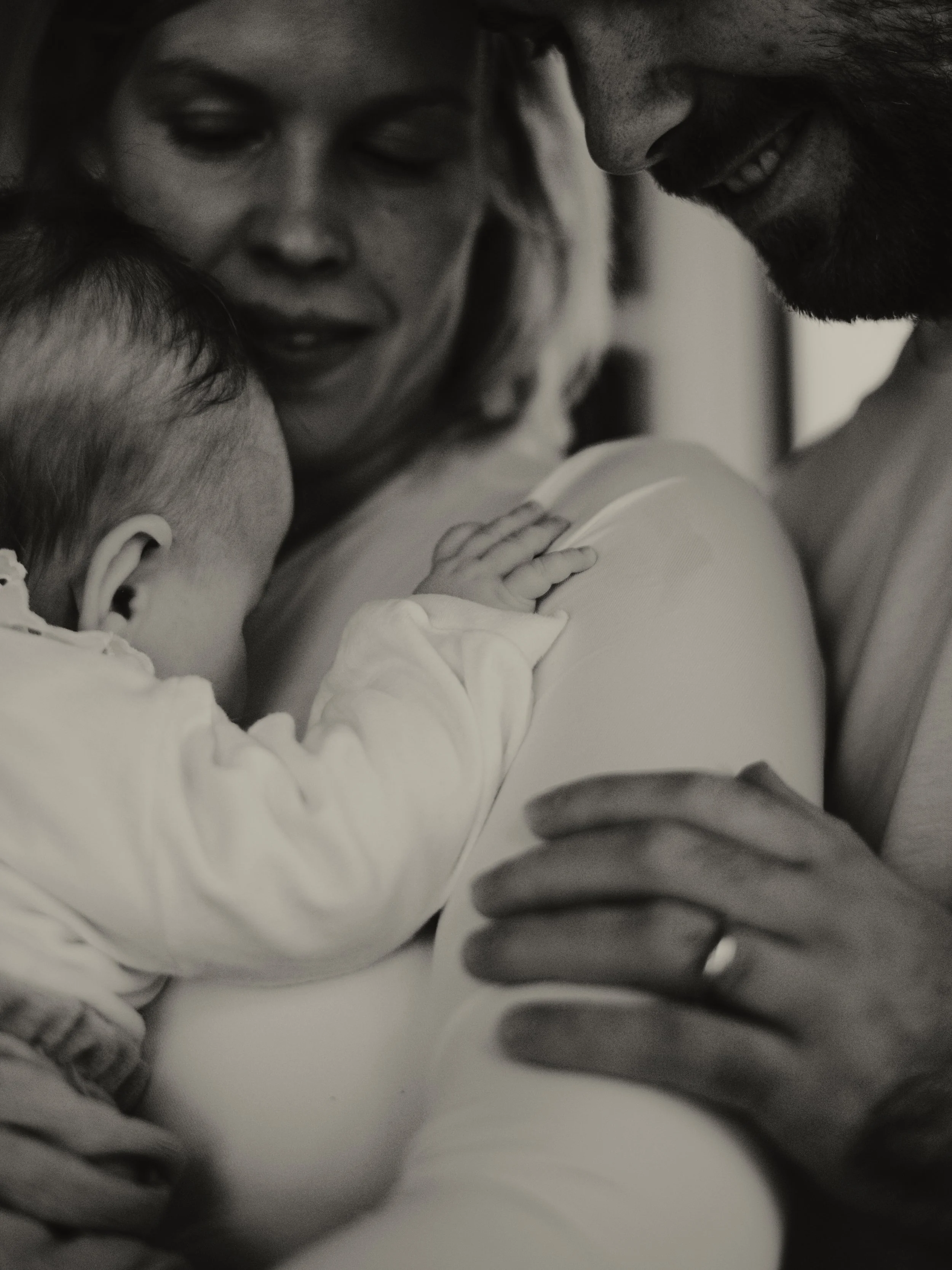 Perhe halailee ja katsoo rakastavasti vauvaa, joka on äidin sylissä.