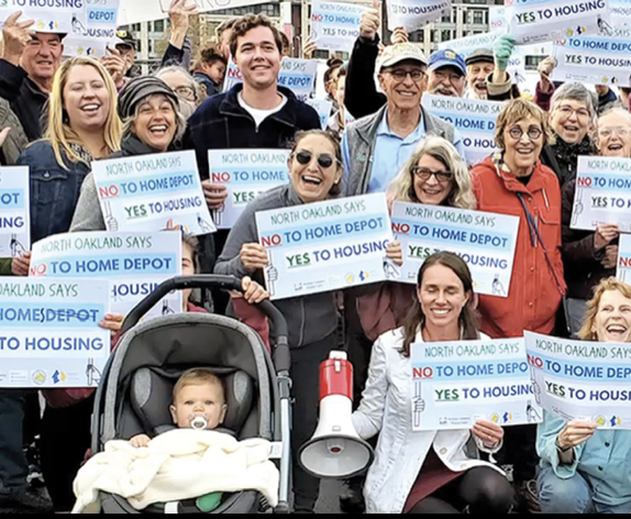Group of diverse people protesting for housing rights, holding signs that read 'Yes to Housing' and 'No to Home Depot' during a day-time rally.