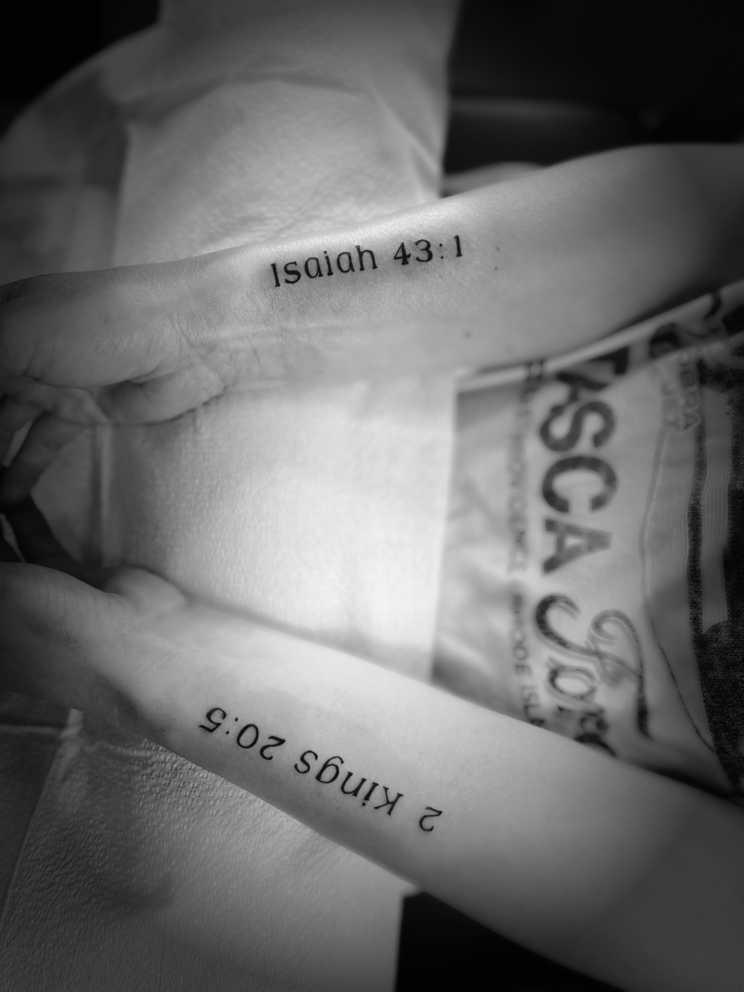 A person holding a rolled piece of paper with the Bible verse Isaiah 43:1 printed on it, covering part of a newspaper or magazine.