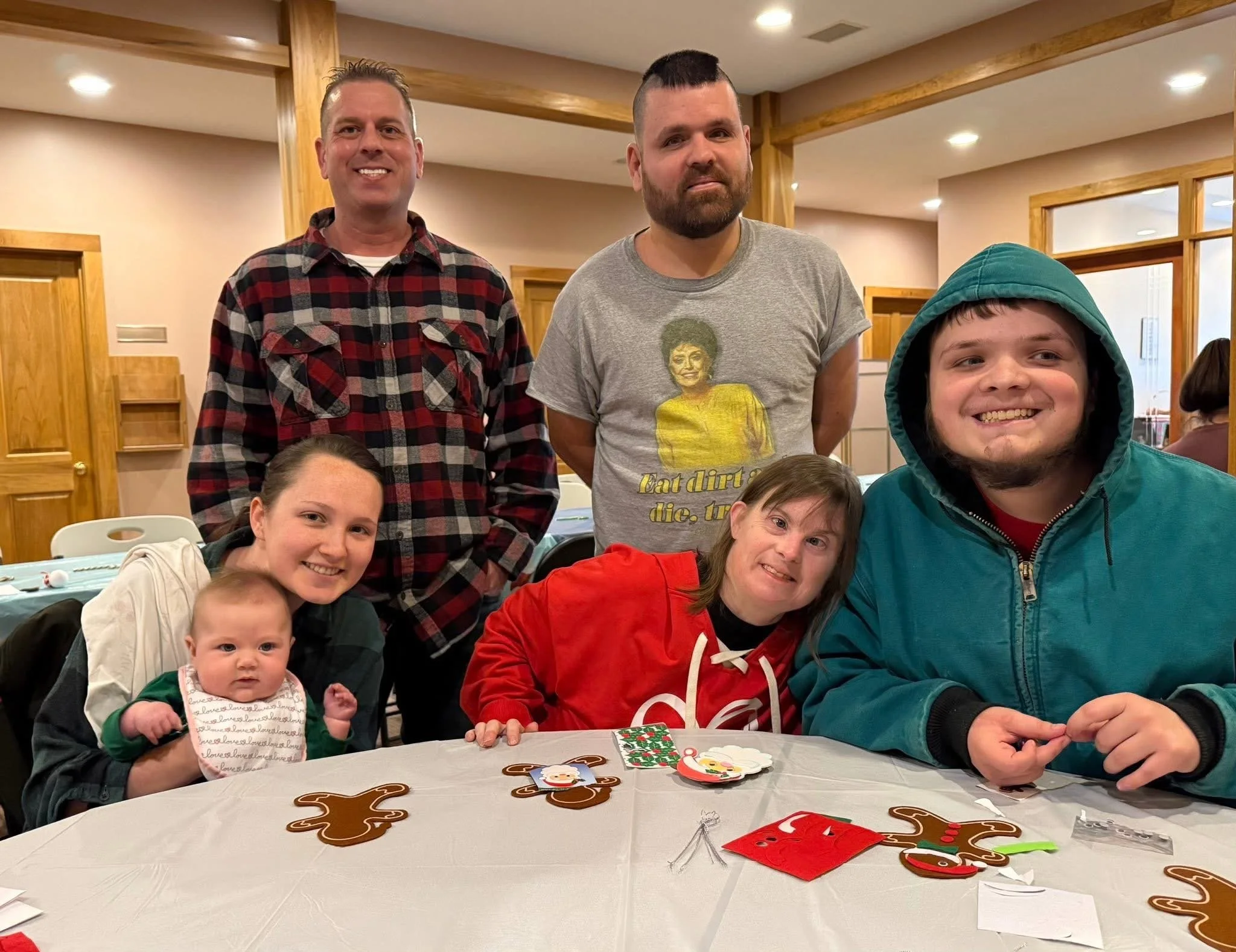 Family gathered around a table with Christmas cookies and decorations, posing for a photo indoors.