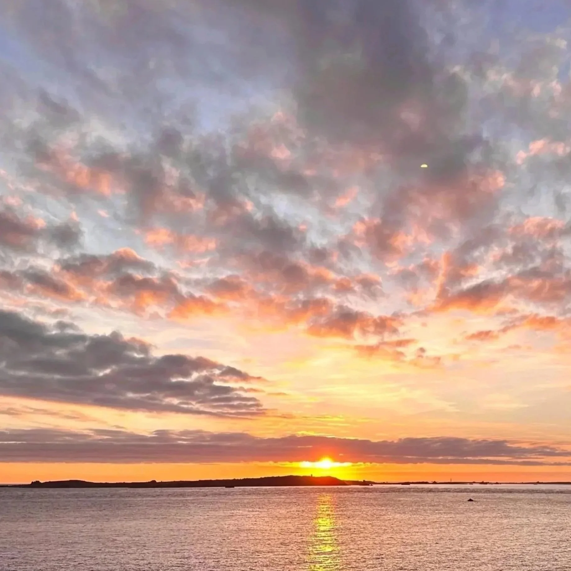 Sunset over the sea in the Isles of Scilly with colorful clouds in the sky.