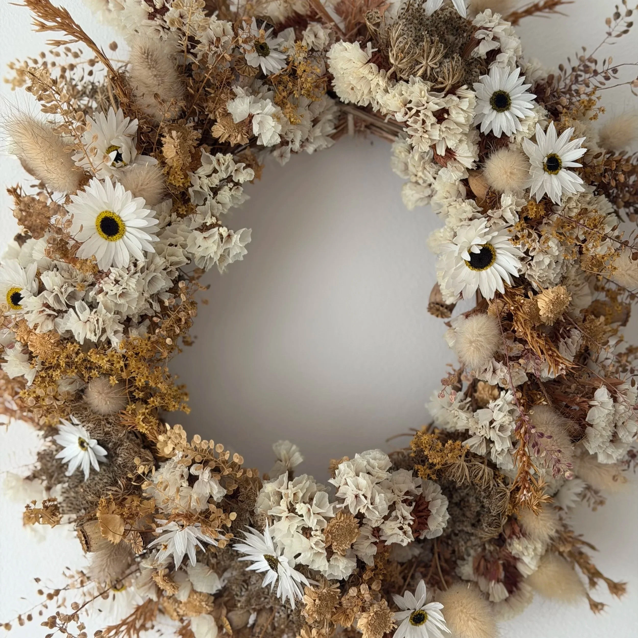 Dried flower wreath with white daisies, beige and brown dried flowers and grasses.
