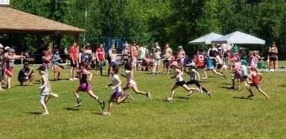 Children running in a race during an outdoor event at a park.