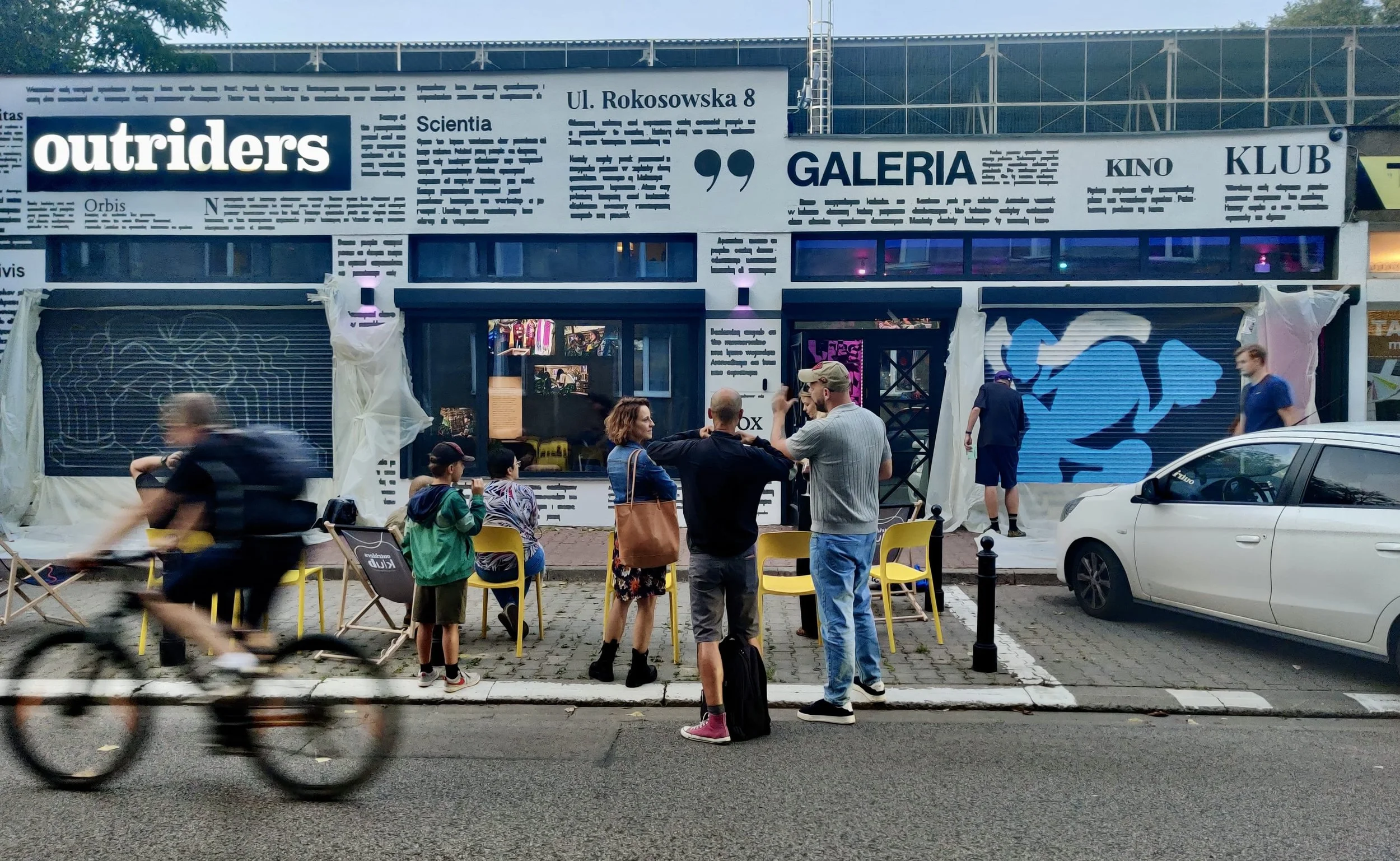 A modern backyard with a swimming pool, lounge chairs, and a house with a patio, surrounded by desert plants and trees.