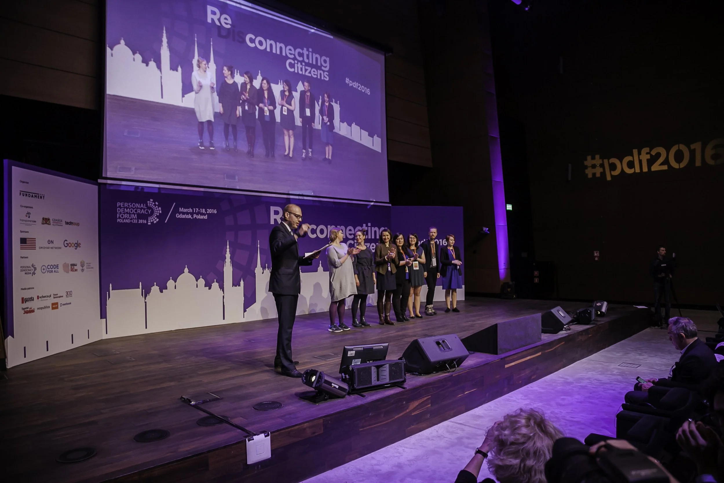 Field of daisies with white petals and orange centers, some flowers in bloom and others budding, with soft sunlight.
