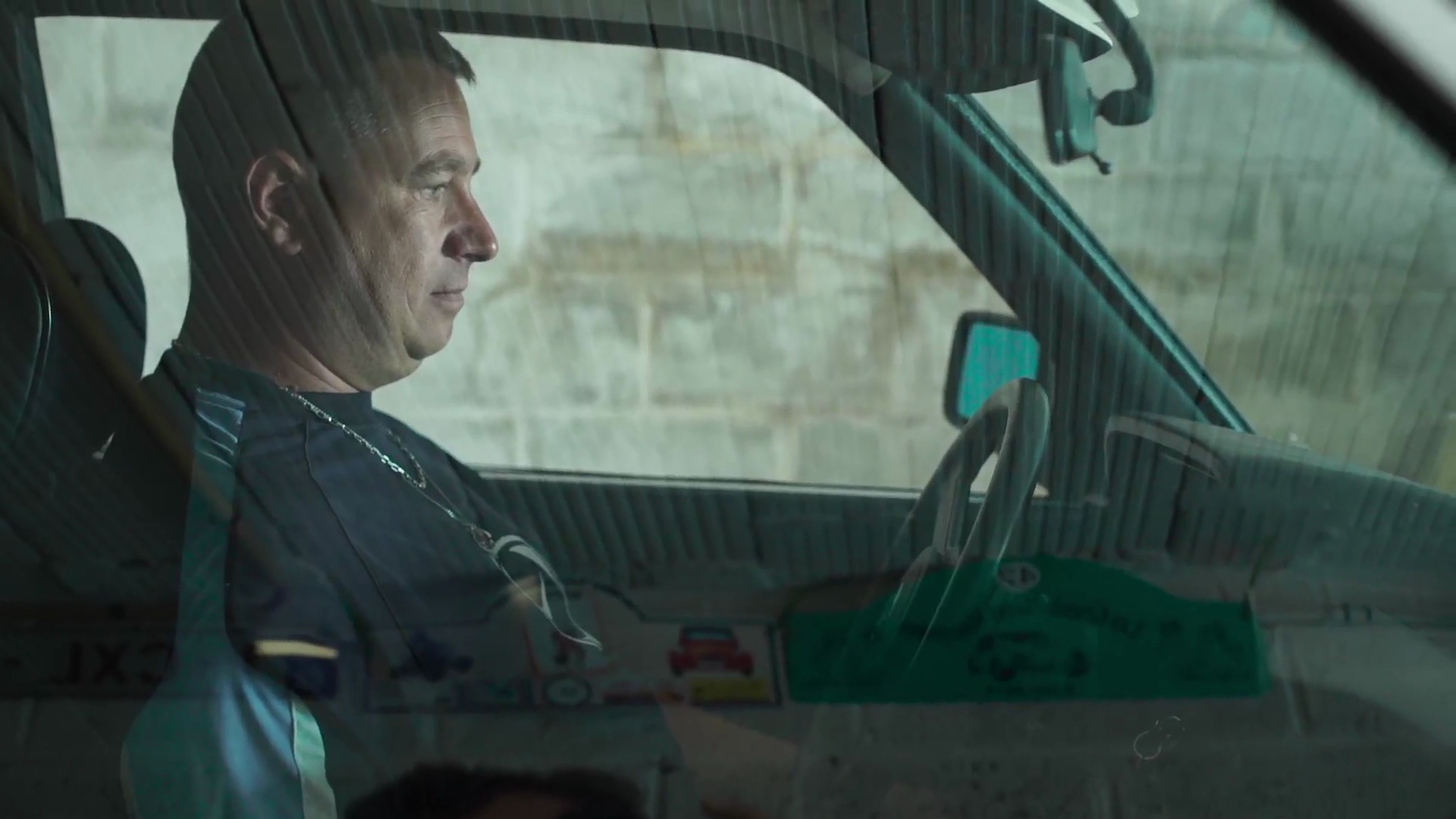 Un homme en uniforme assis dans la cabine d'un véhicule, regardant vers l'avant.