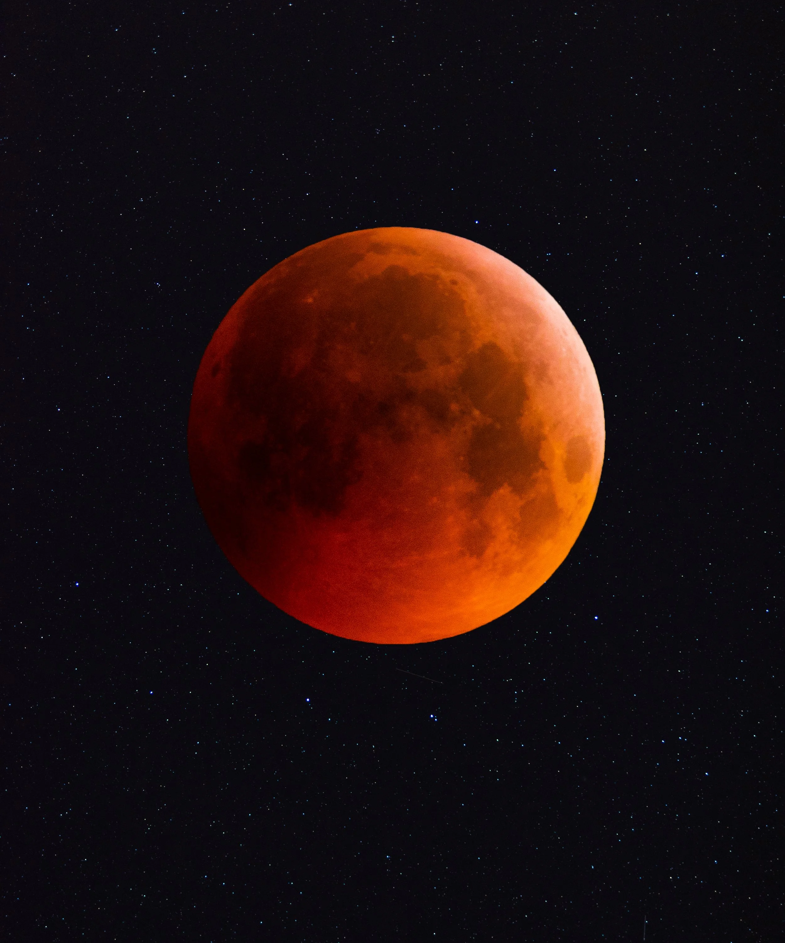 A blood moon during a lunar eclipse with a starry night sky in the background.