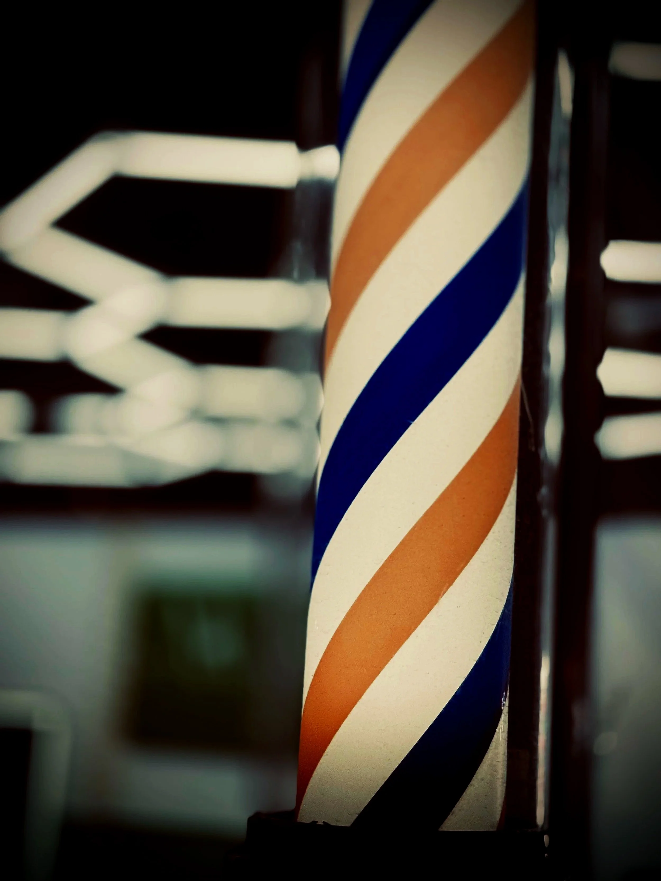 Barbería clásica con barra de pelo en espiral de colores azul, blanco y naranja.