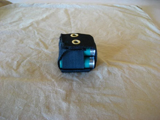 A small black device with two visible slots for batteries, resting on a crinkled beige surface.