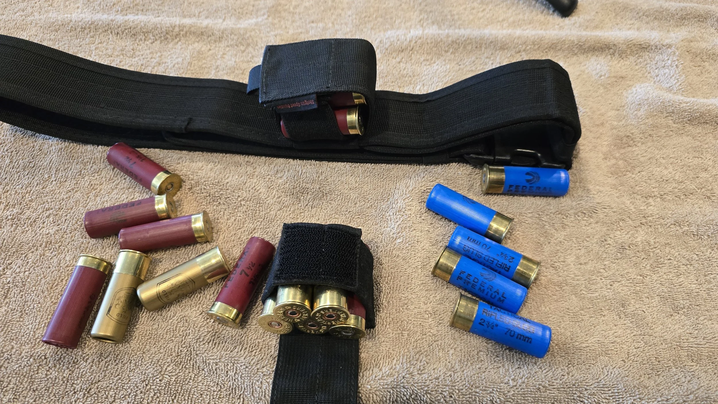 Shotgun shells in red and blue on a beige towel with black strap holders.