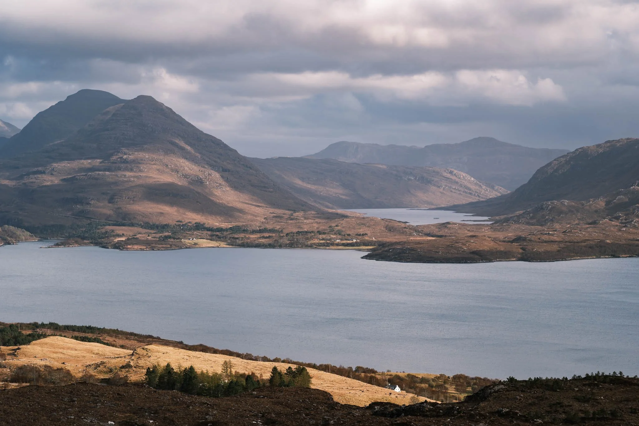 Highland - Scotland - Paysage de montagnes avec un Loch, ciel nuageux et terrain vallonné.