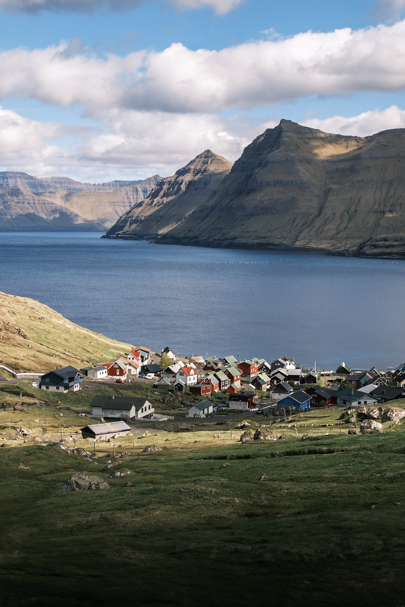 Faroe Islands - Petite ville de maisons colorées située au bord d'un lac entouré de montagnes. .  Reportage outdoor, mise en valeur du territoire et tourisme durable par Guillaume Donsimoni.