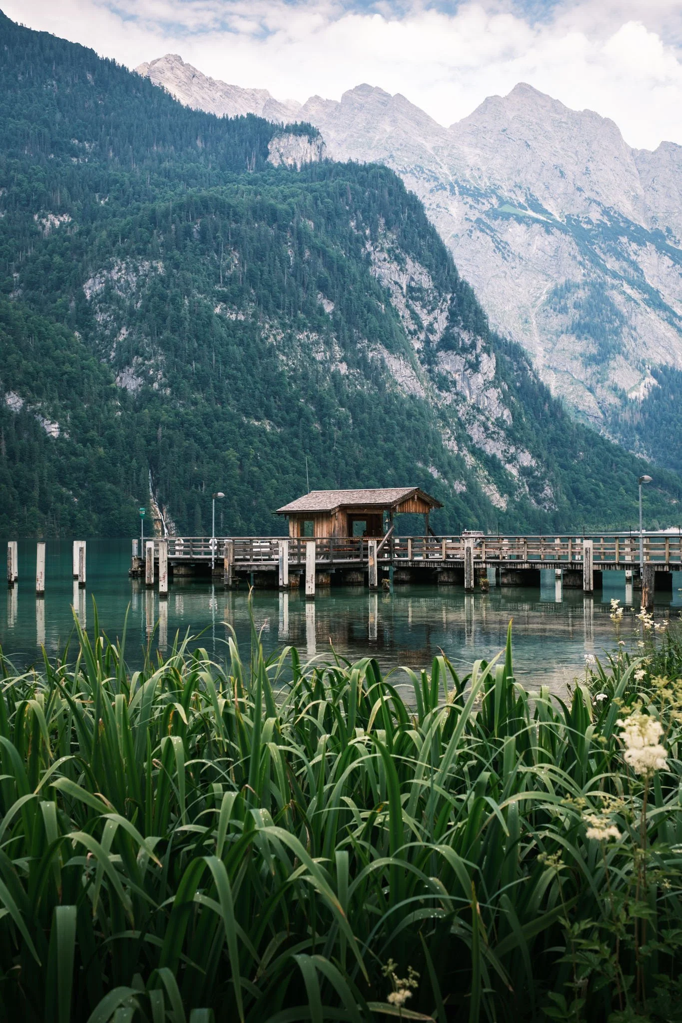 Austria - Un quai en bois s'étend sur un lac entouré de montagnes avec une cabane en bois et une végétation dense en premier plan. Reportage outdoor, mise en valeur du territoire et tourisme durable par Guillaume Donsimoni