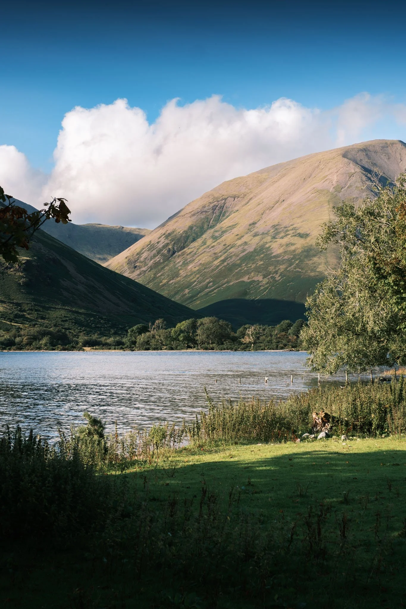 Lake District - Paysage de montagnes verdoyantes avec un lac au premier plan et un ciel bleu avec quelques nuages.  Reportage outdoor, mise en valeur du territoire et tourisme durable par Guillaume Donsimoni.
