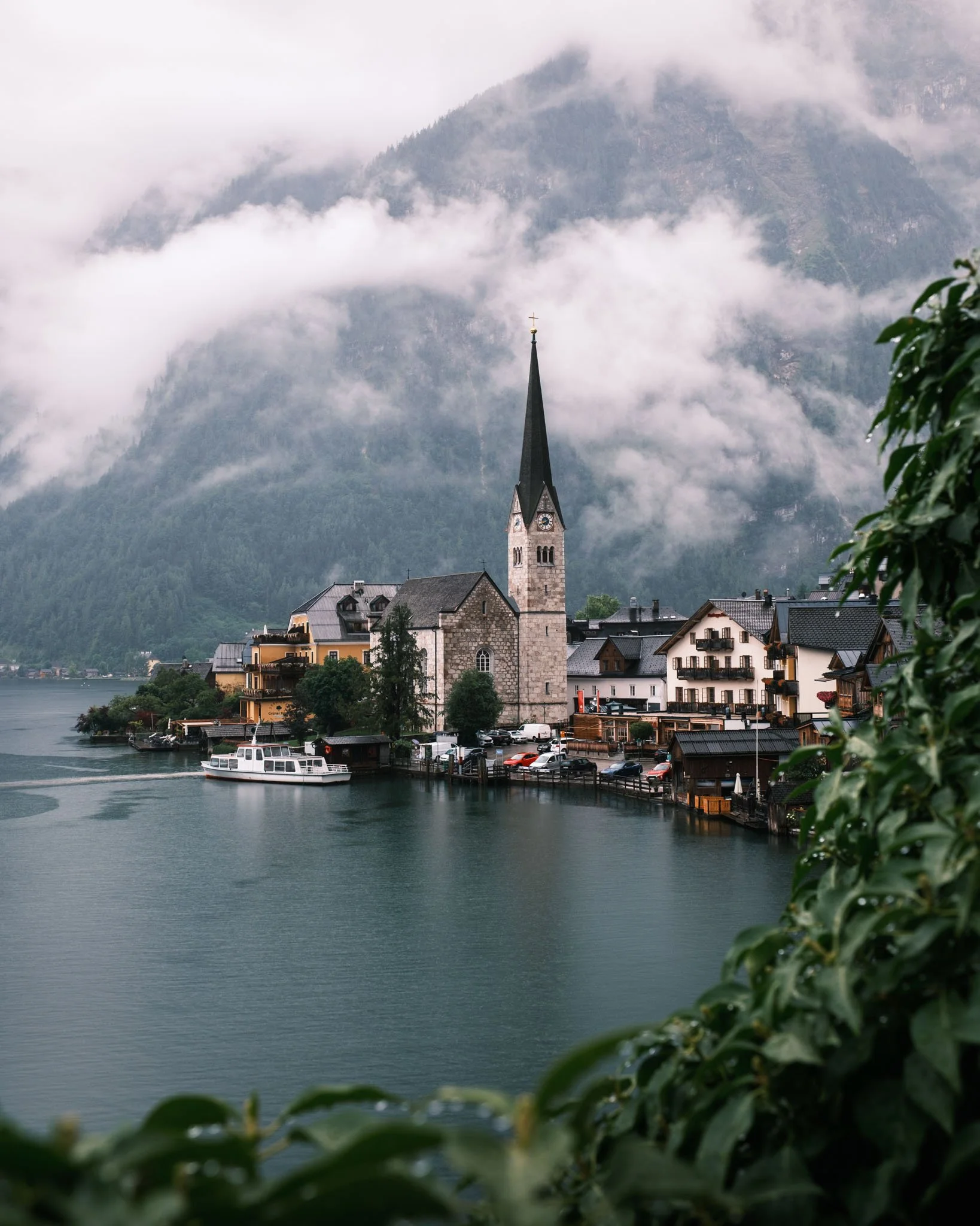 Tyrol - Ville d'Hallstatt avec église au bord d'un lac entourée de montagnes brumeuses. Reportage outdoor, mise en valeur du territoire et tourisme durable par Guillaume Donsimoni
