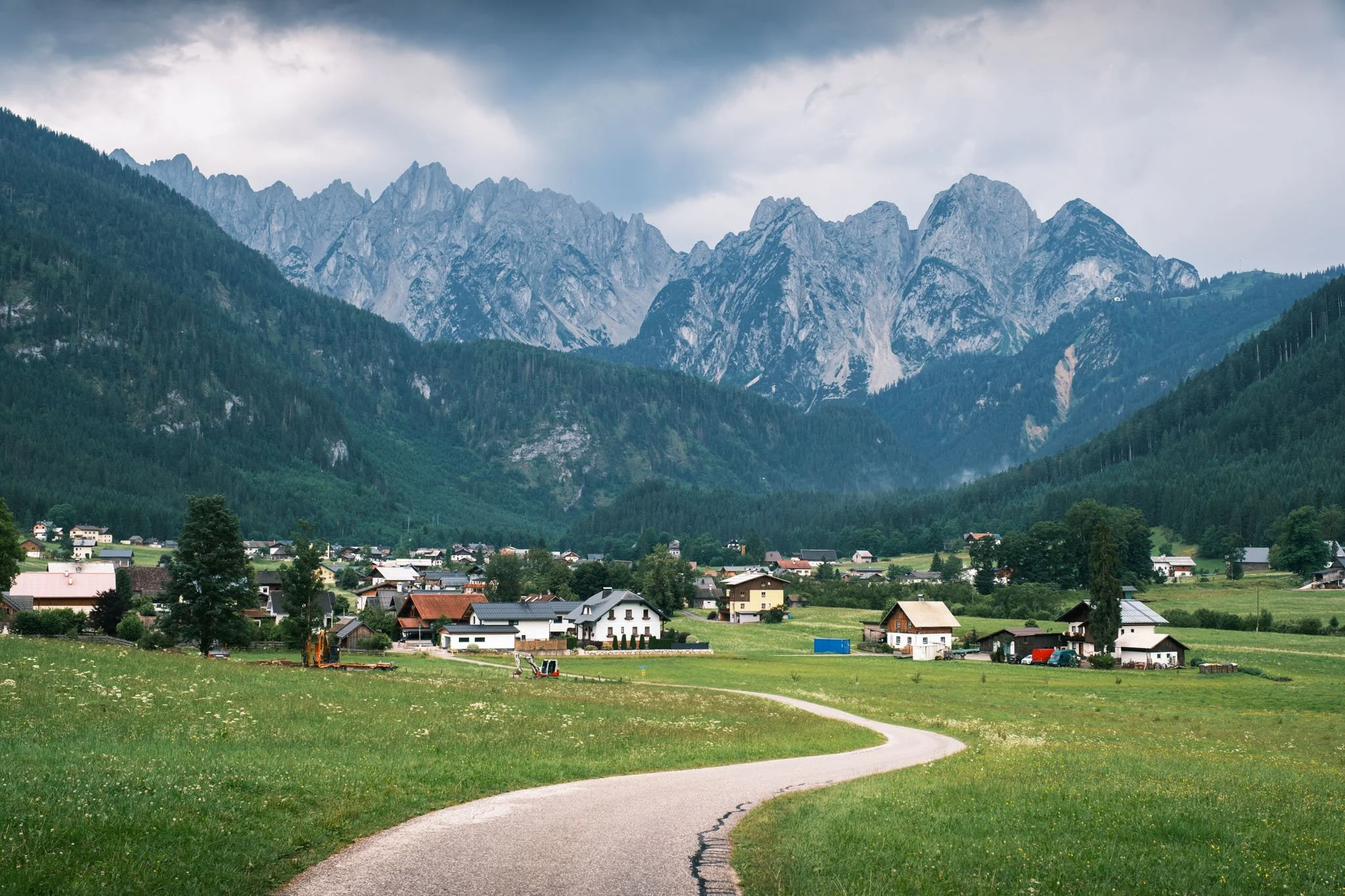 Tyrol - Vue d'un village avec des maisons, entouré de champs verts et de montagnes rocheuses en arrière-plan. Reportage outdoor, mise en valeur du territoire et tourisme durable par Guillaume Donsimoni