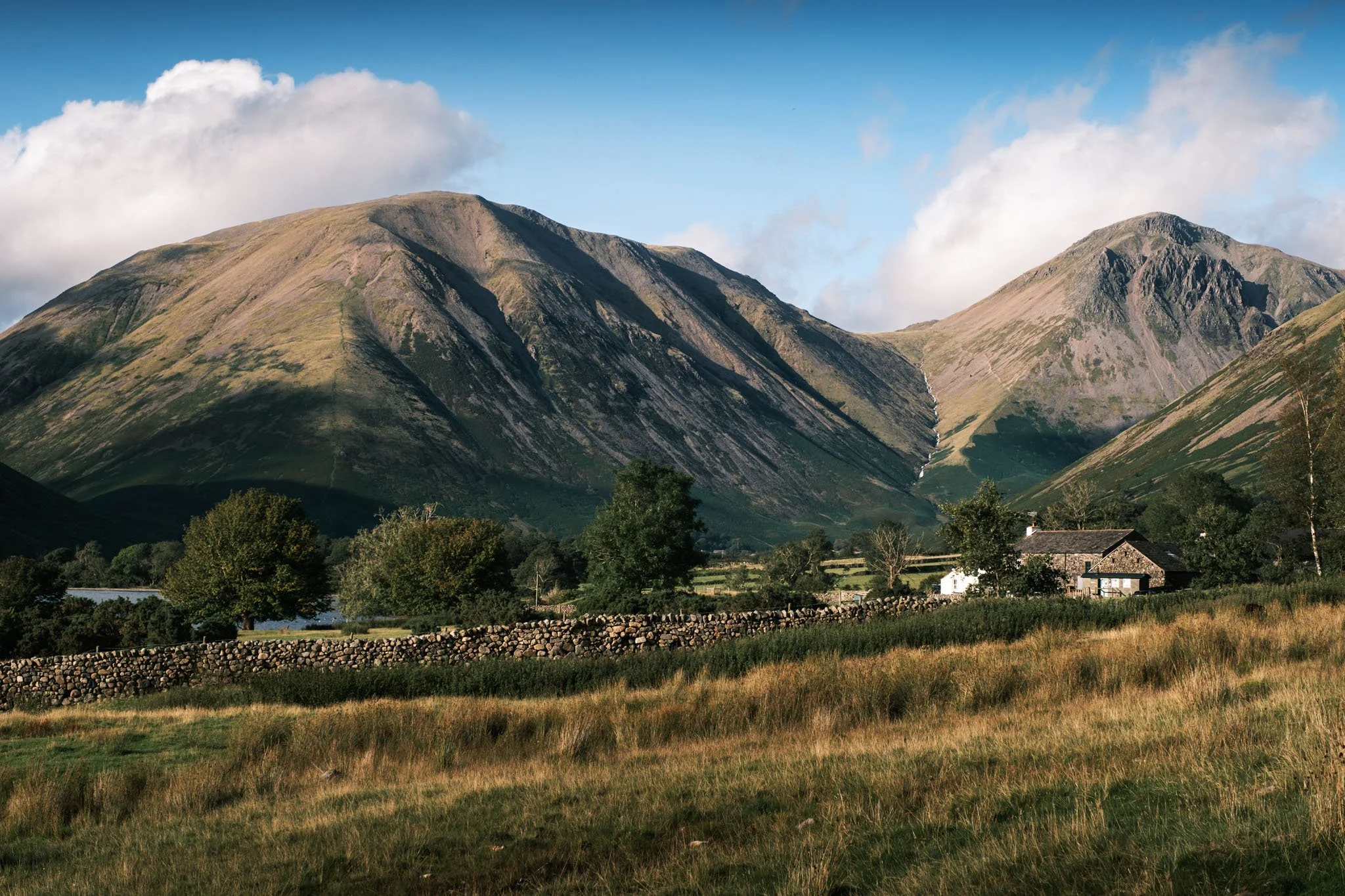 Lake District - Paysage de montagnes avec une ferme en pierre et un champ en avant-plan.  Reportage outdoor, mise en valeur du territoire et tourisme durable par Guillaume Donsimoni.