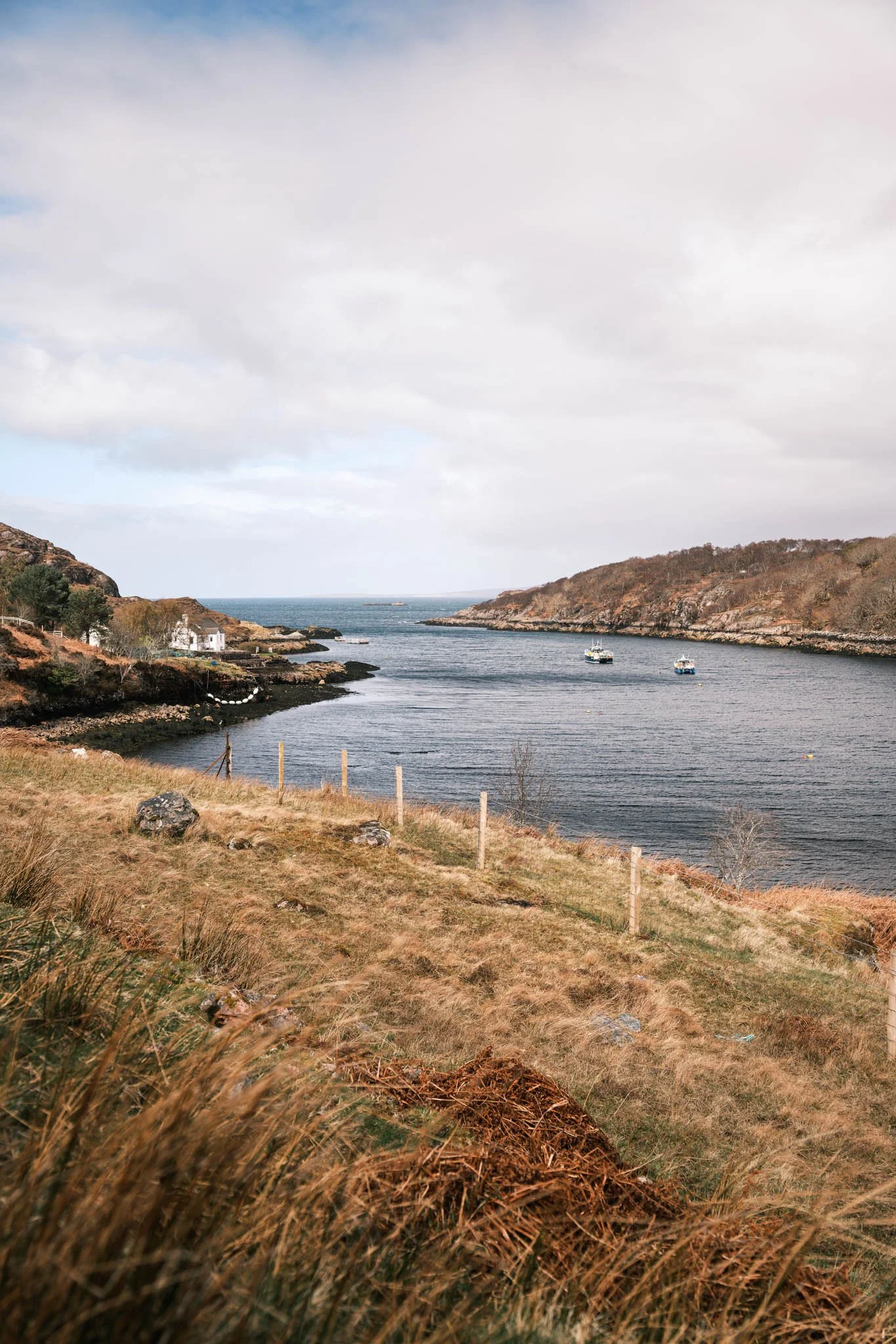 Highland - Scotland - Vue du littoral avec des bateaux, des collines rocheuses et un ciel nuageux.