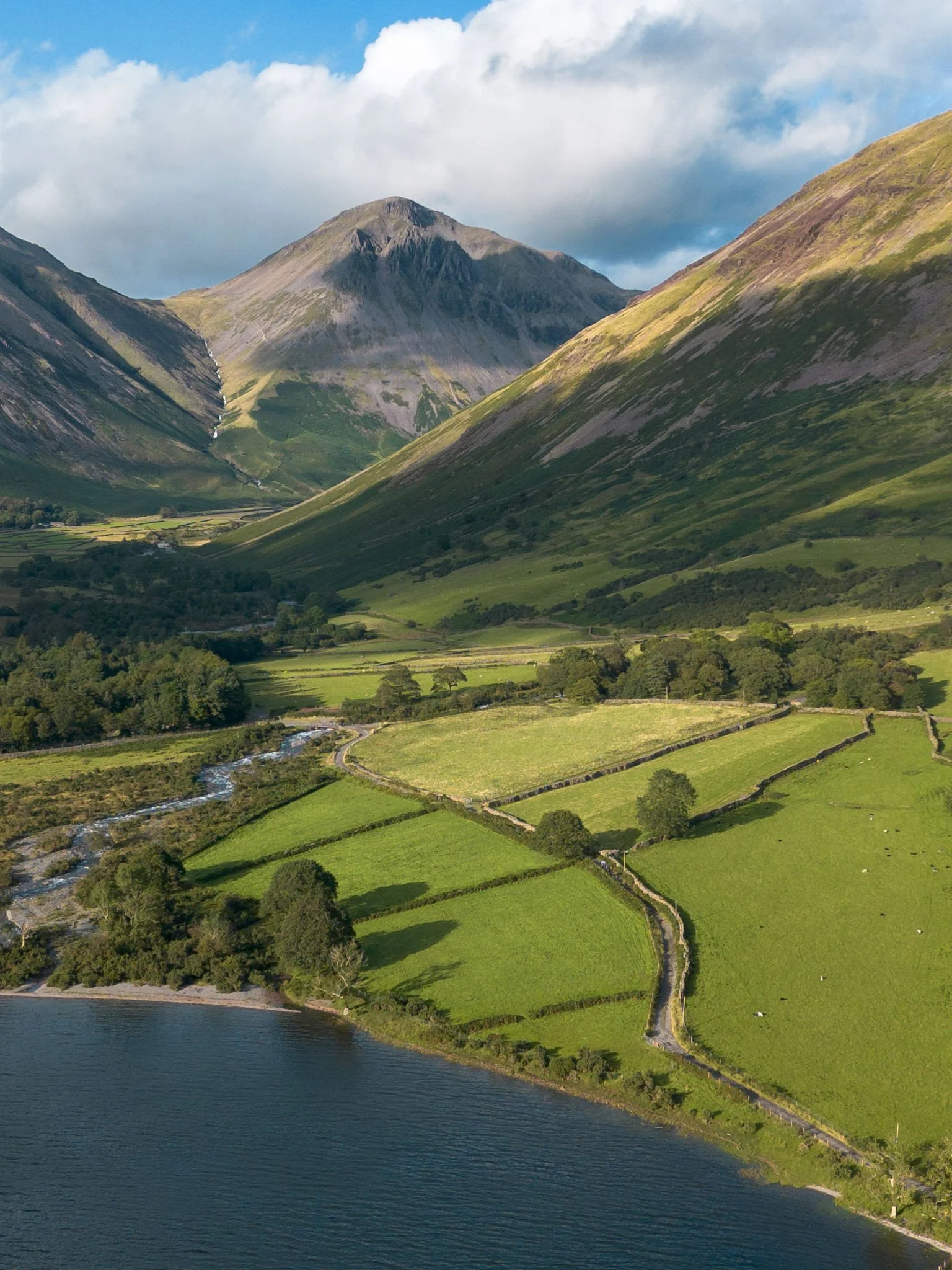 Lake District - Paysage de montagnes verdoyantes avec des champs, un lac et des nuages dans le ciel.  Reportage outdoor, mise en valeur du territoire et tourisme durable par Guillaume Donsimoni.