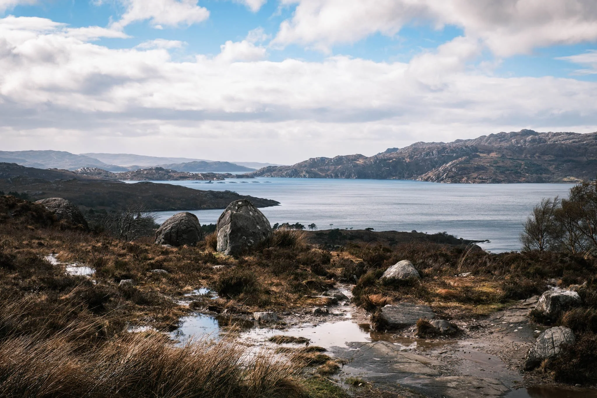 Highland - Scotland - Paysage avec des montagnes, un Loch et un ciel nuageux, vue depuis une zone rocheuse et herbeuse.