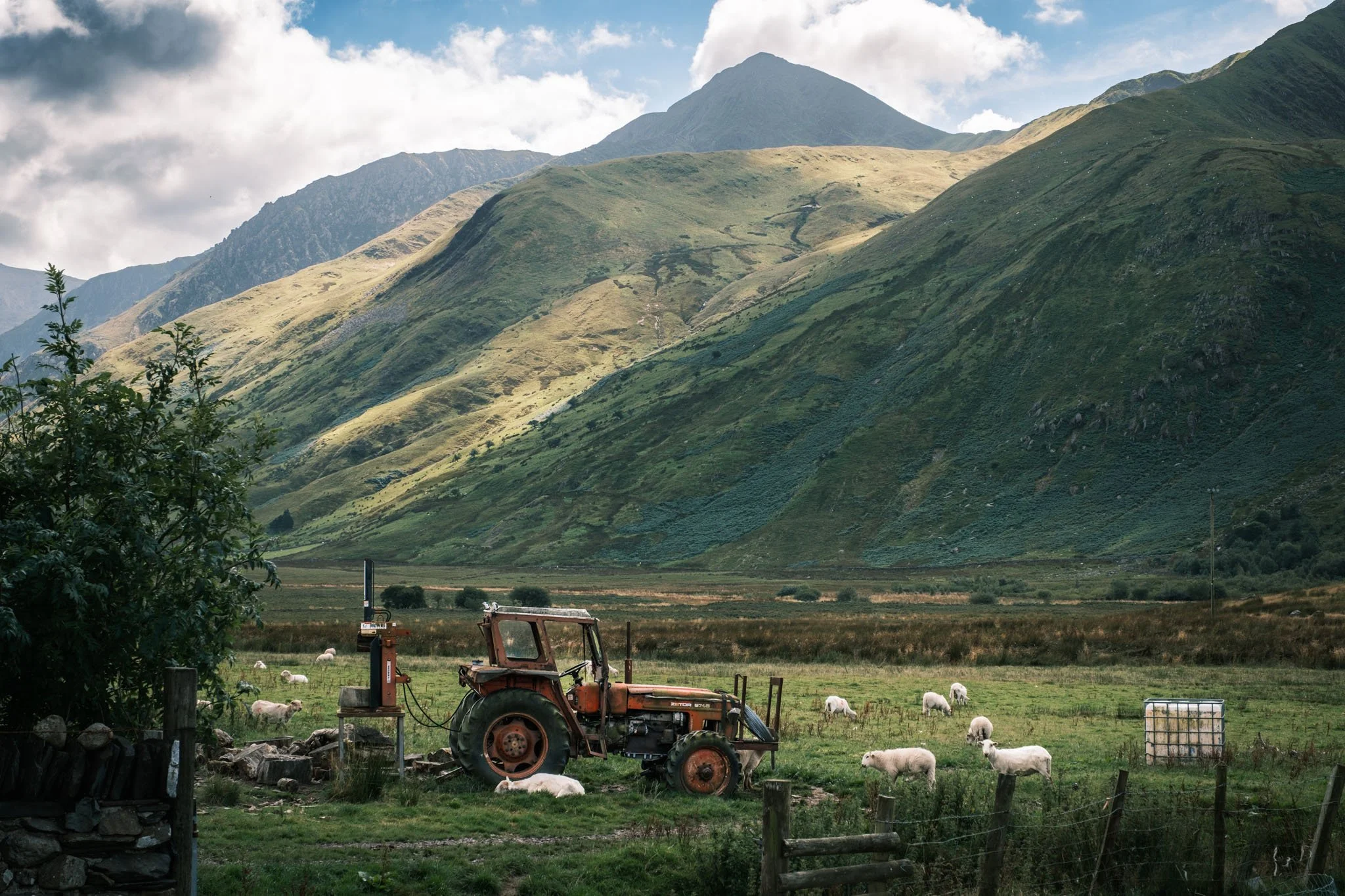 Wales - Green mountain landscape with an old tractor, sheep in a meadow, and a partially cloudy sky. Outdoor reportage, regional promotion, and sustainable tourism by Guillaume Donsimoni.