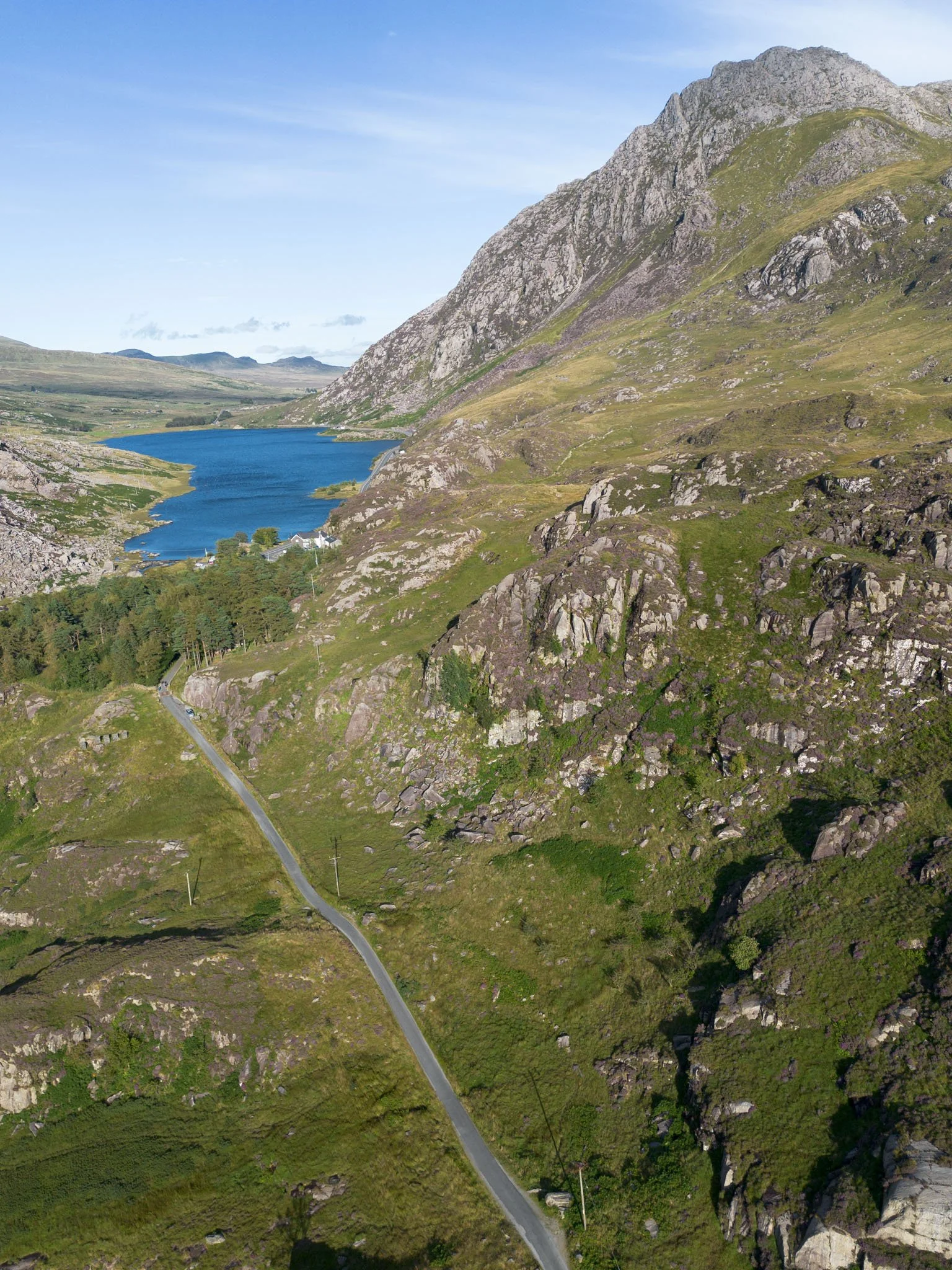 Wales - Landscape of green mountains with a blue lake, a winding road, and a clear sky. Snowdonia National Park. Outdoor reportage, regional promotion, and sustainable tourism by Guillaume Donsimoni.