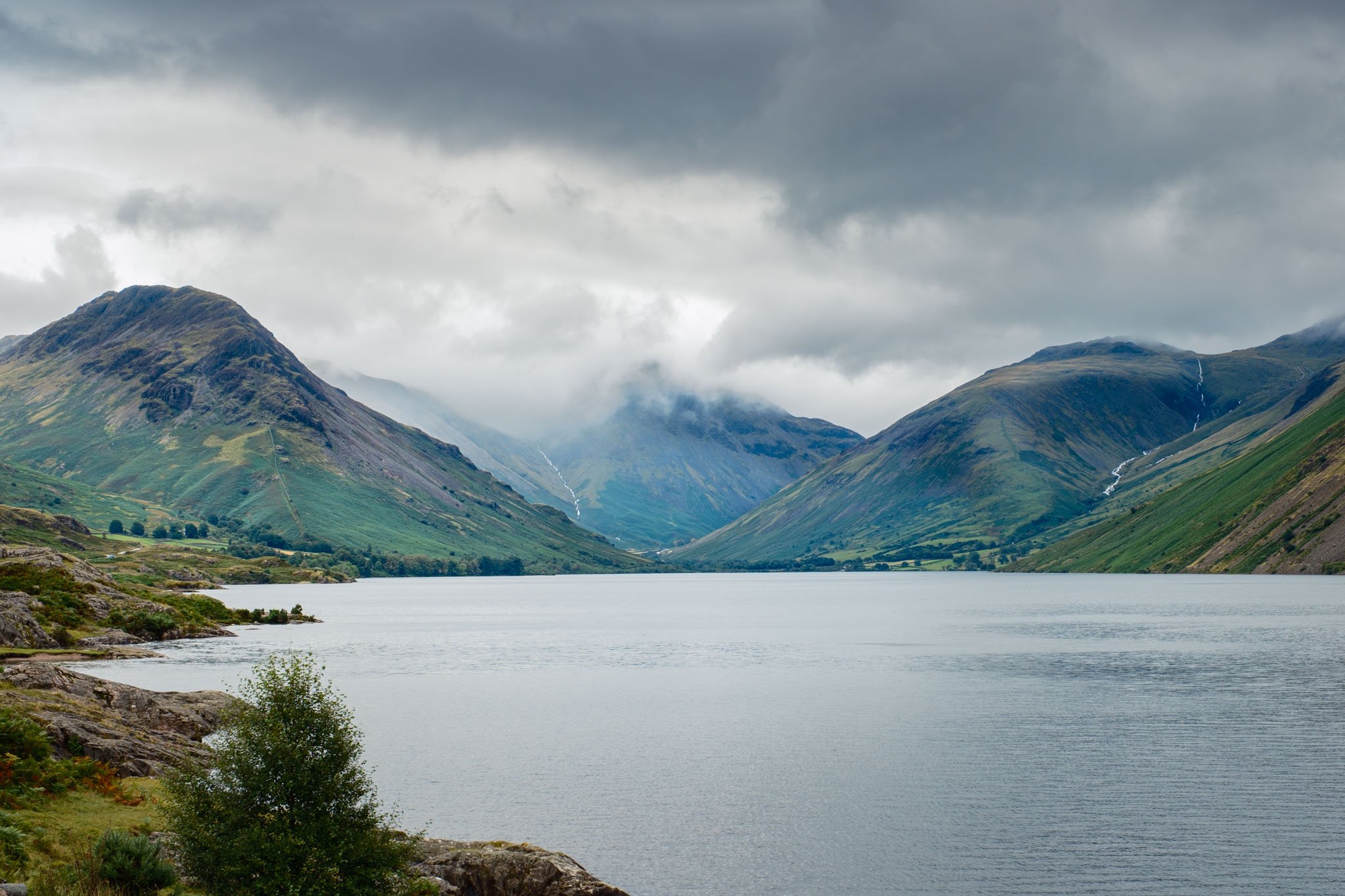 Lake District - Paysage de montagnes verdoyantes entourant un lac calme sous un ciel nuageux.  Reportage outdoor, mise en valeur du territoire et tourisme durable par Guillaume Donsimoni.