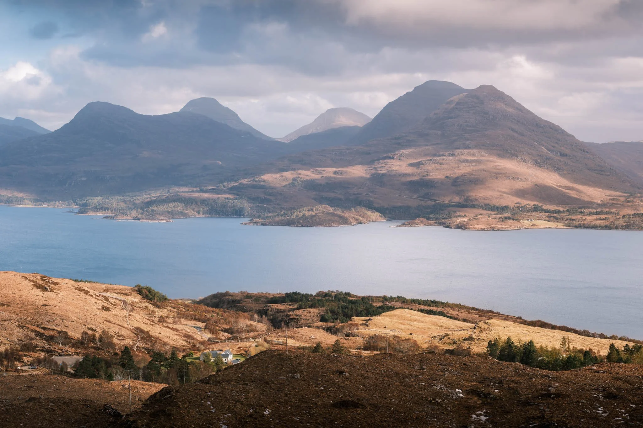 Highland - Scotland - Paysage de montagnes avec un Loch au premier plan et des collines en dessous, ciel nuageux.