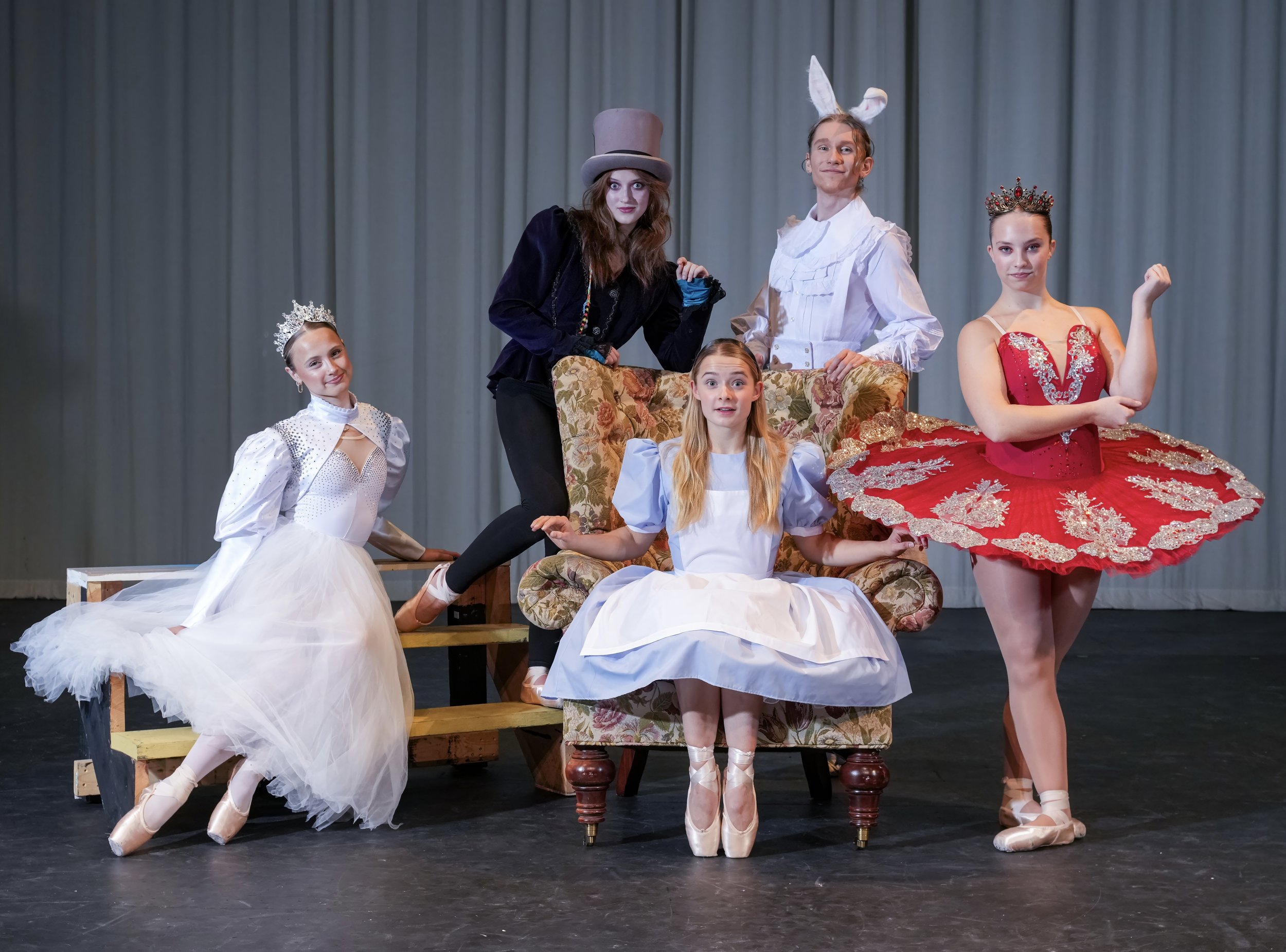 Young ballerinas in ornate costumes and headpieces posing backstage with theatrical characters.