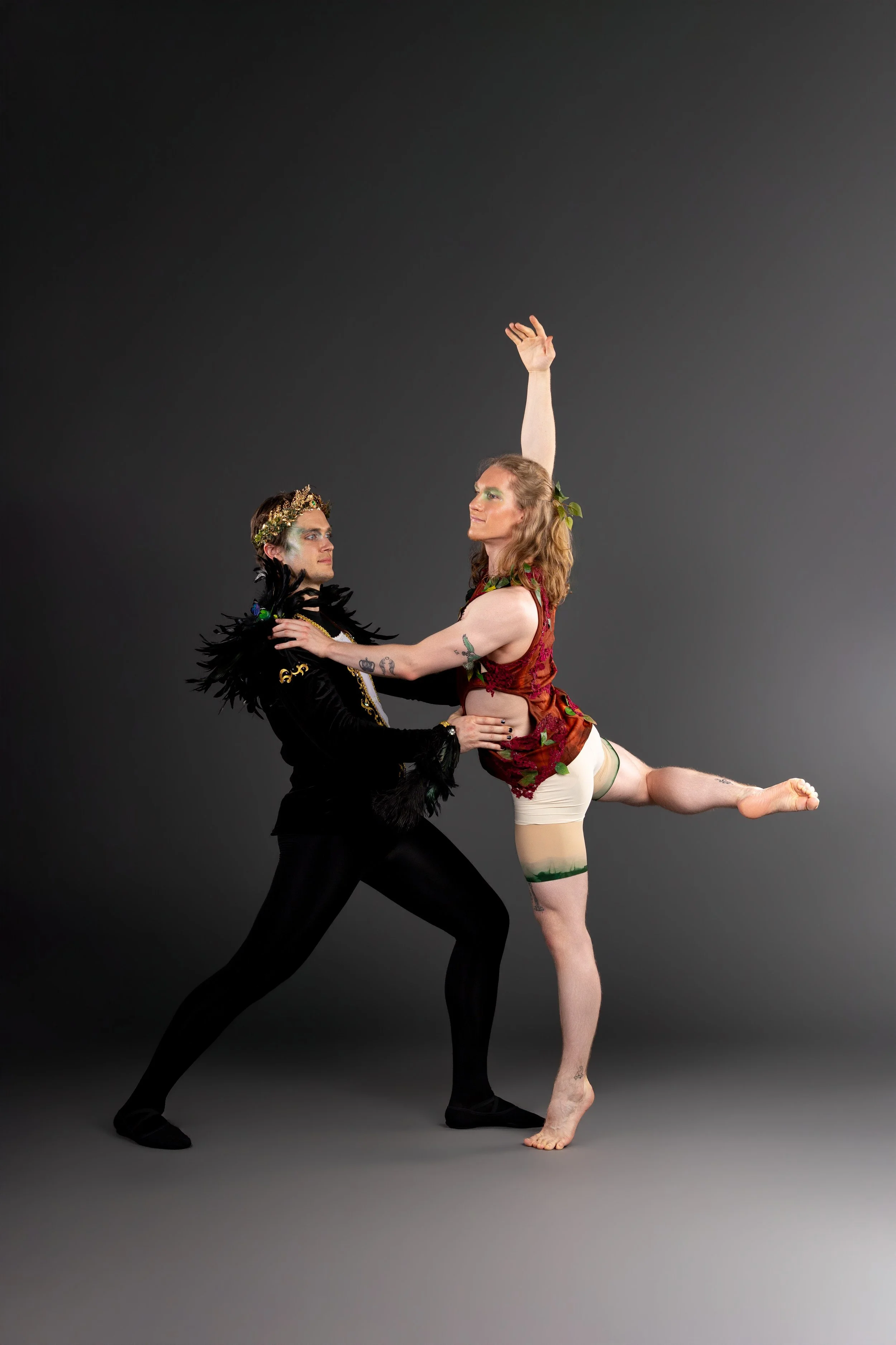 A ballet dancer performing a leap against a black background, wearing white tights and a sleeveless top.