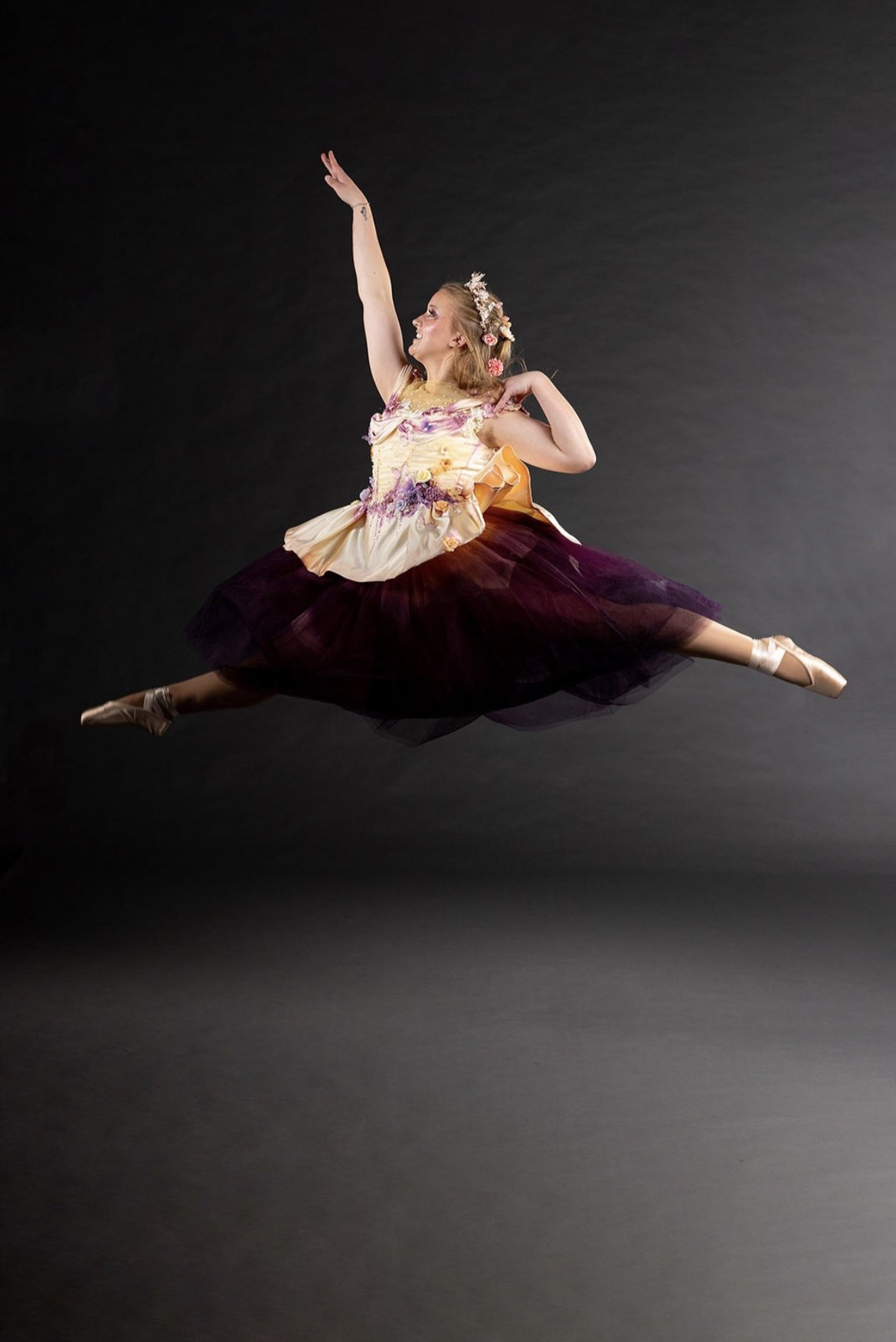 A person in dance attire performing a pose in a dark room with stage lights and rigging.