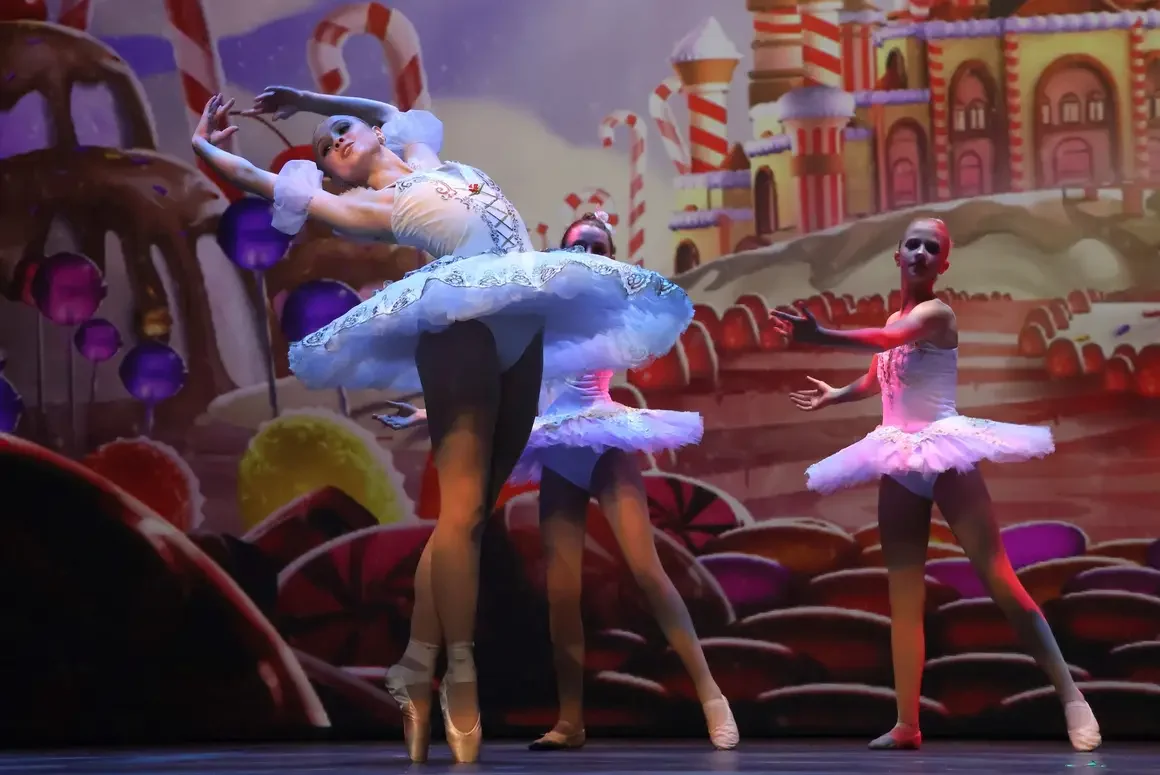 Ballet dancers performing on stage with a colorful gingerbread and candy-themed backdrop.