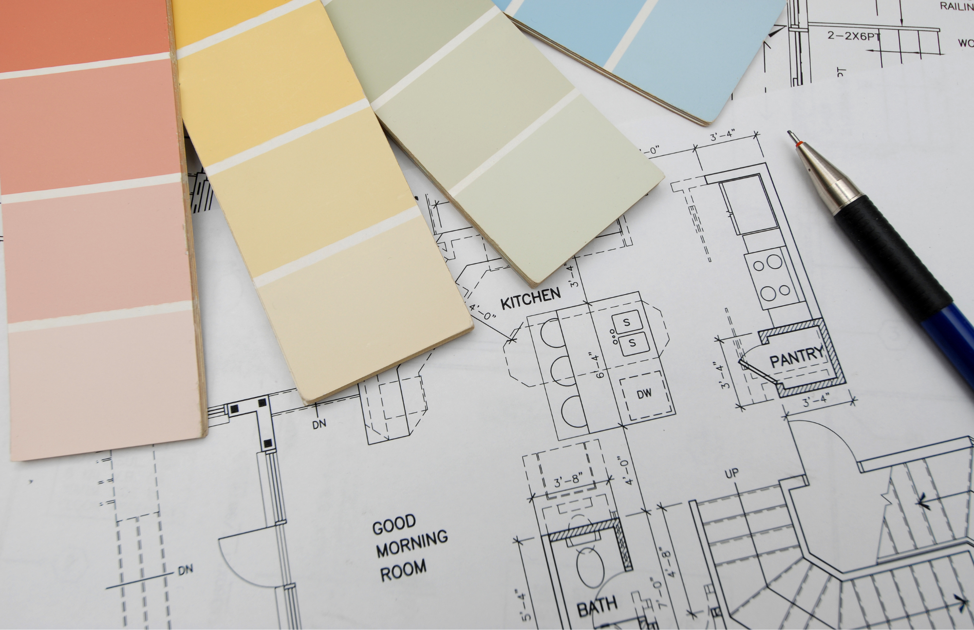 Color swatches placed on a blueprint of a house layout, featuring rooms labeled 'Kitchen,' 'Pantry,' 'Good Morning Room,' and 'Bath,' with a pen nearby.