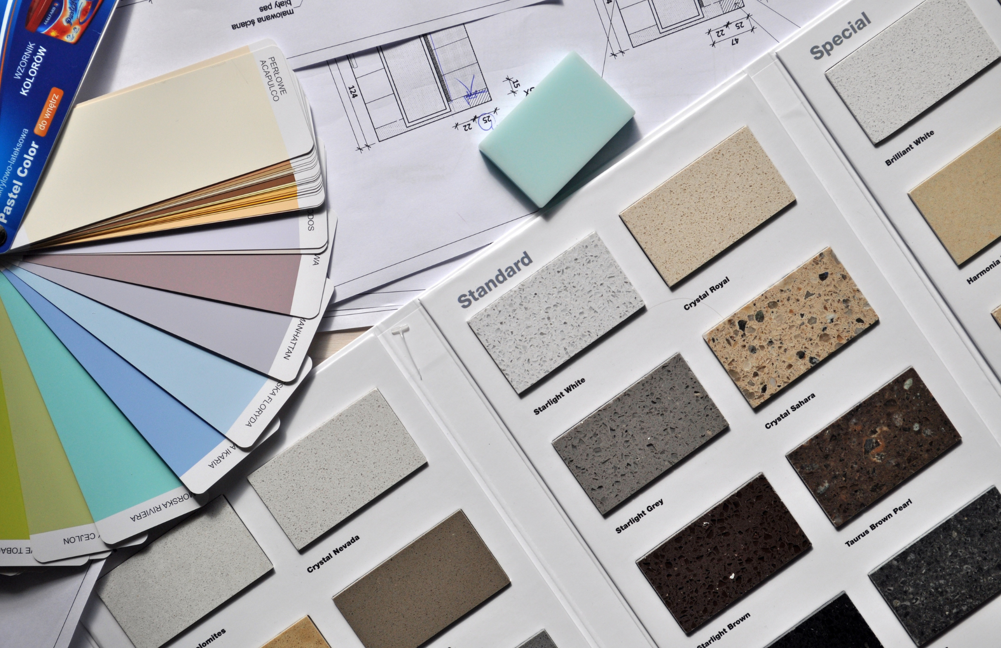 Sample color and texture swatches of various countertop materials, including standard, special, and different shades of granite and quartz, placed on design plans.