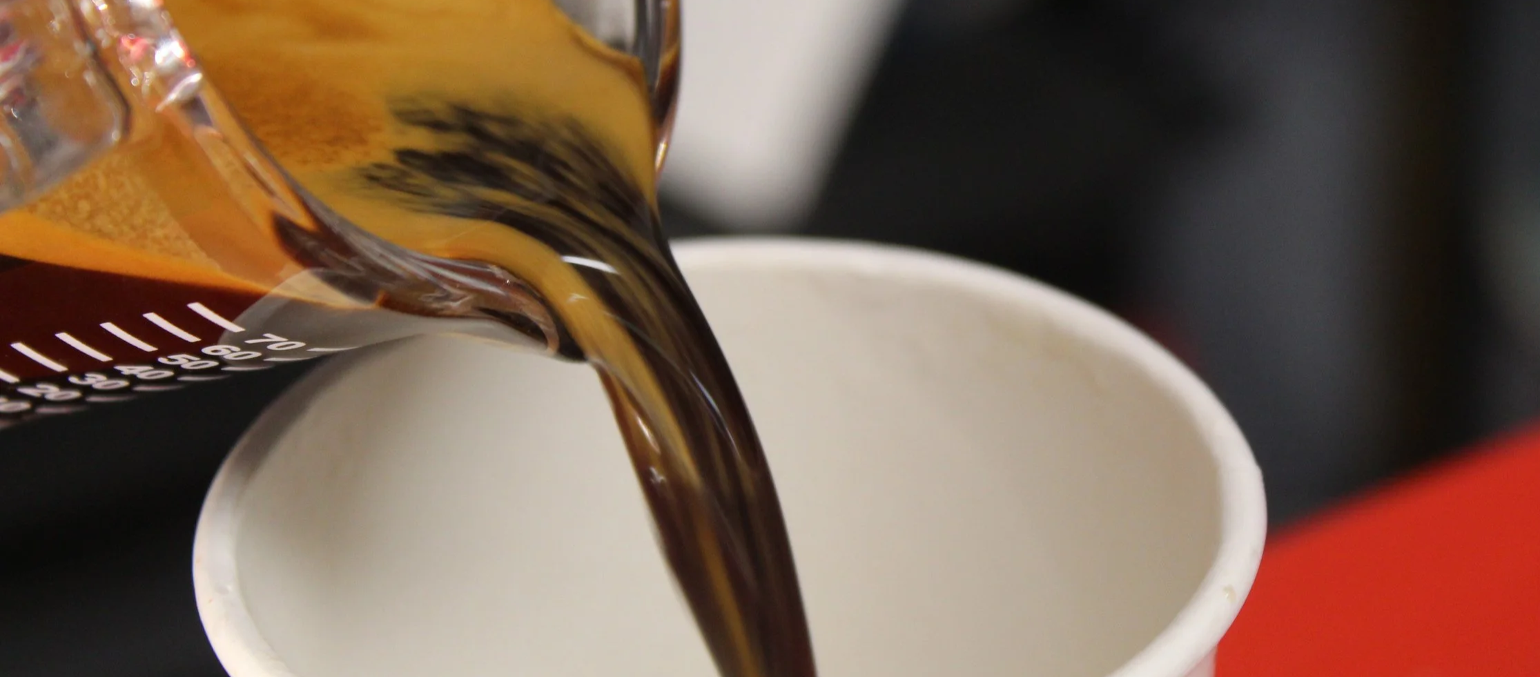 Pouring coffee from a bottle into a white cup.
